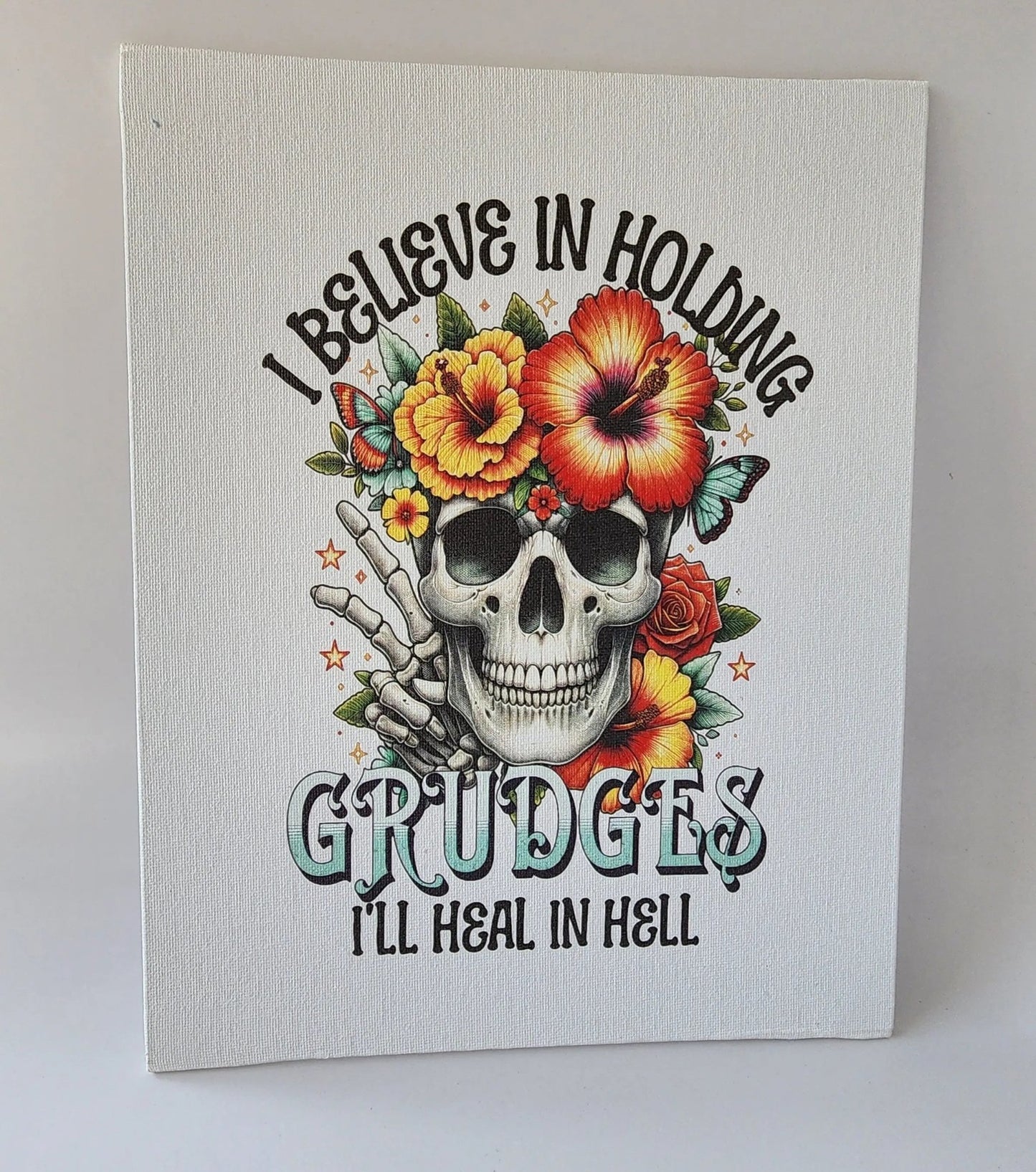 The Mirabilia Boutique "I Believe in Holding Grudges" Canvas Print (8x10) features a skull with flowers and dark humor text, perfect Gothic decor for bold spaces.
