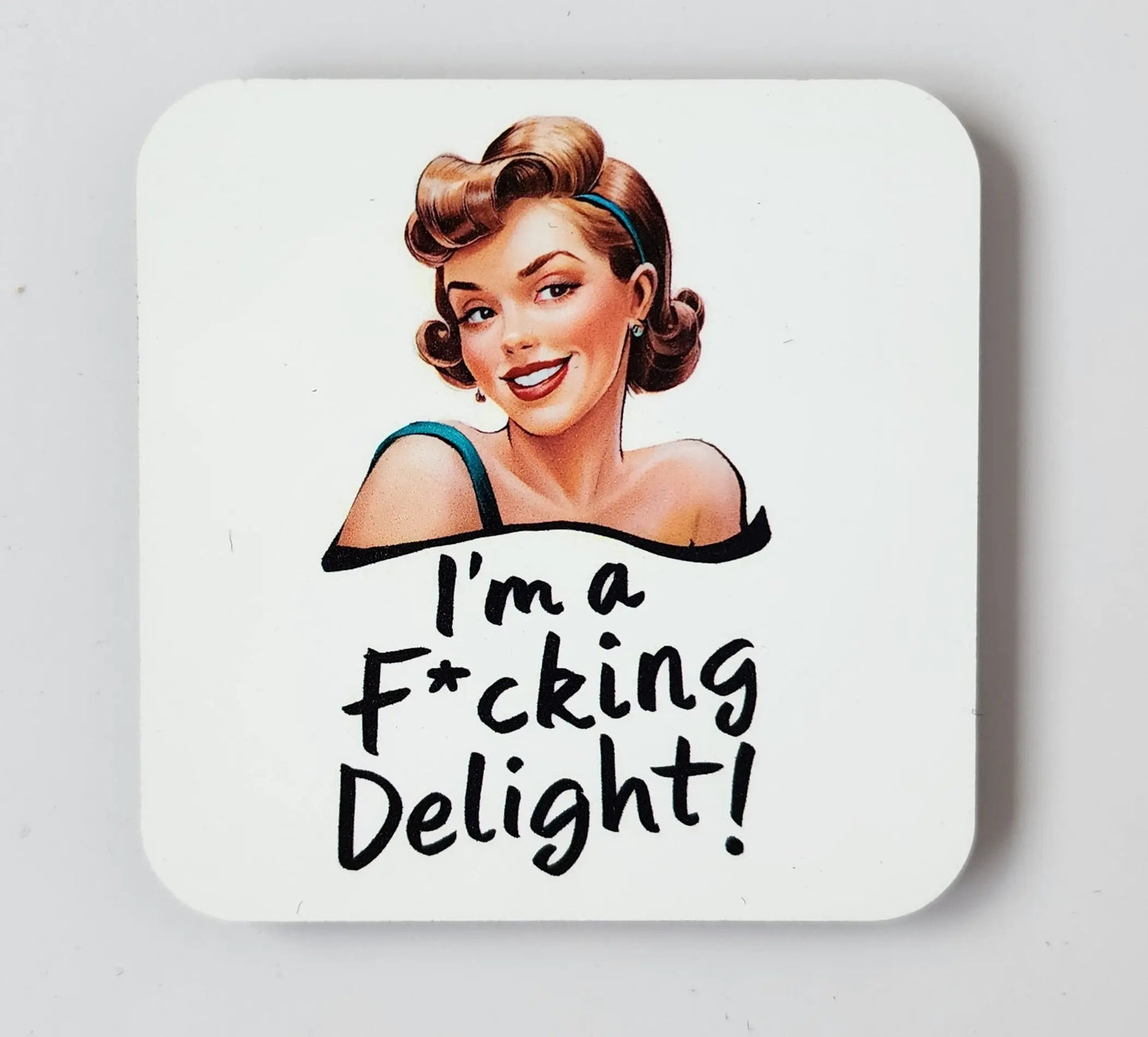 The "I'm a Fucking Delight" snarky magnet from Mirabilia Boutique showcases a smiling woman with a vintage hairstyle and makeup. The playful, bold handwriting below her reads, "I'm a F*cking Delight!" against an entirely white background.