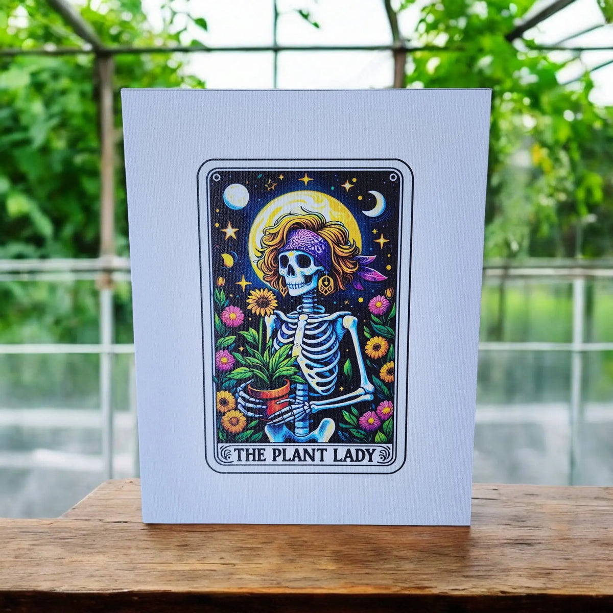 The Plant Lady Canvas Art by Mirabilia Boutique features a skeleton in a headband and jewelry holding a potted plant, surrounded by flowers, stars, and moons on wood. UV printed 8x10 wall decor—perfect funny gift for plant moms.