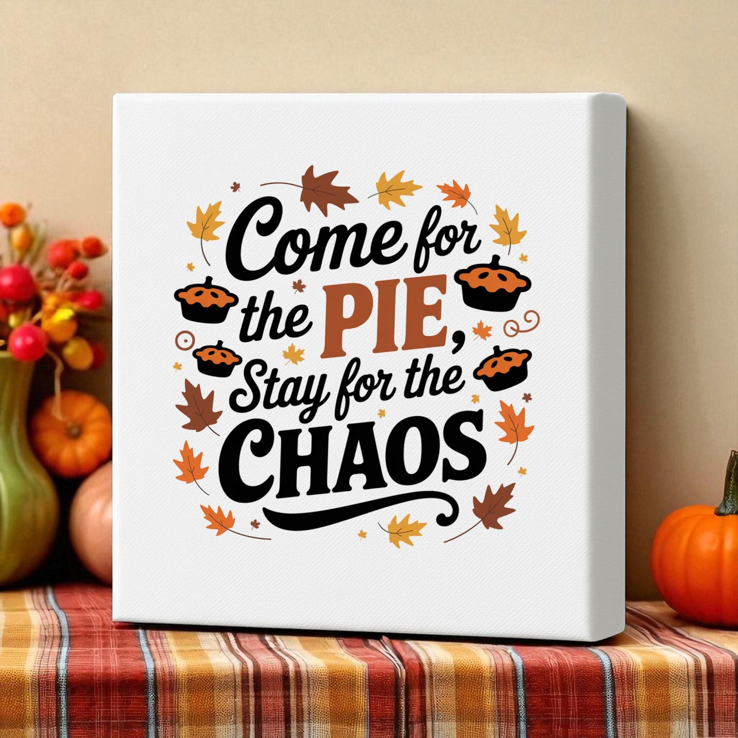 The Mirabilia Boutique's "Come for the Pie Chaos Art" funny Thanksgiving canvas features autumn leaves and pies, perfect as festive decor on a plaid tablecloth beside pumpkins and fall foliage.