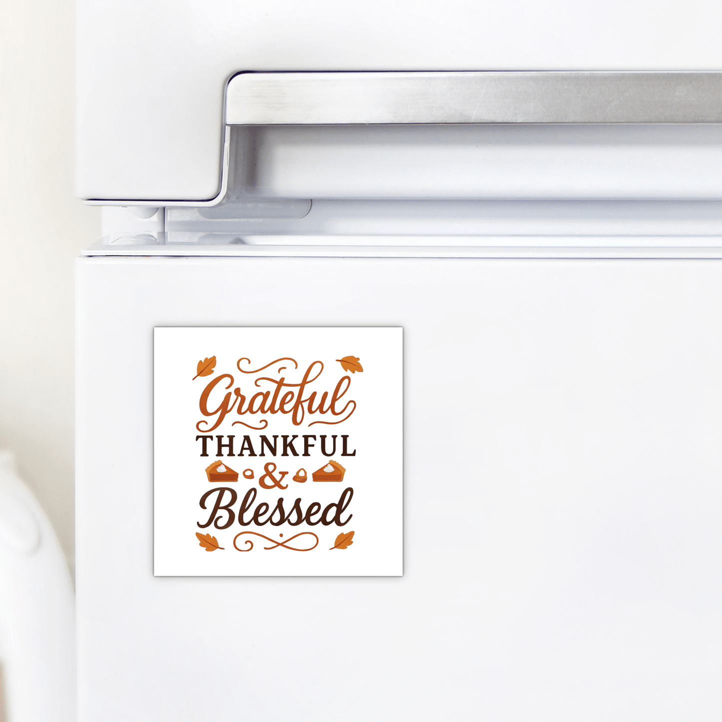 A white fridge features the Mirabilia Boutique Grateful Thankful Blessed Magnet, a square fall magnet with brown script and leaf and pie designs—ideal Thanksgiving decor or gift.