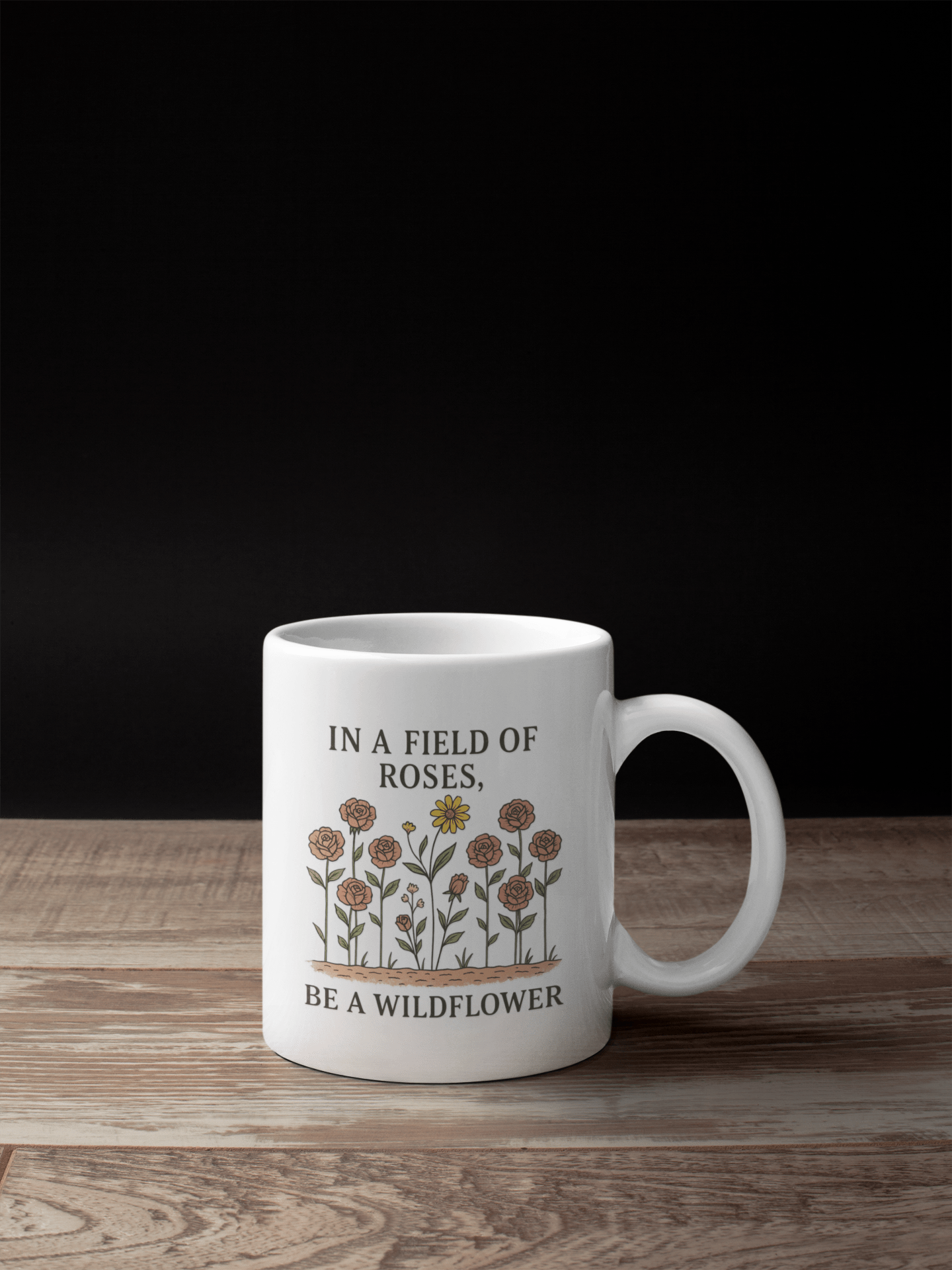 The Be a Wildflower Mug | Inspirational Ceramic Coffee Cup by Mirabilia Boutique features “IN A FIELD OF ROSES, BE A WILDFLOWER” and a standout yellow wildflower among pink roses, perfect for uplifting your day.