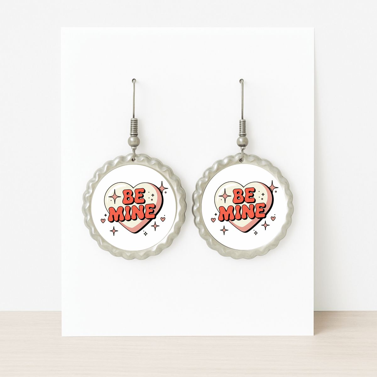 Mirabilia Boutique’s Be Mine Heart Earrings feature a retro scalloped design with bold red “BE MINE” hearts—displayed on a white card, they make a cute Valentine jewelry gift.