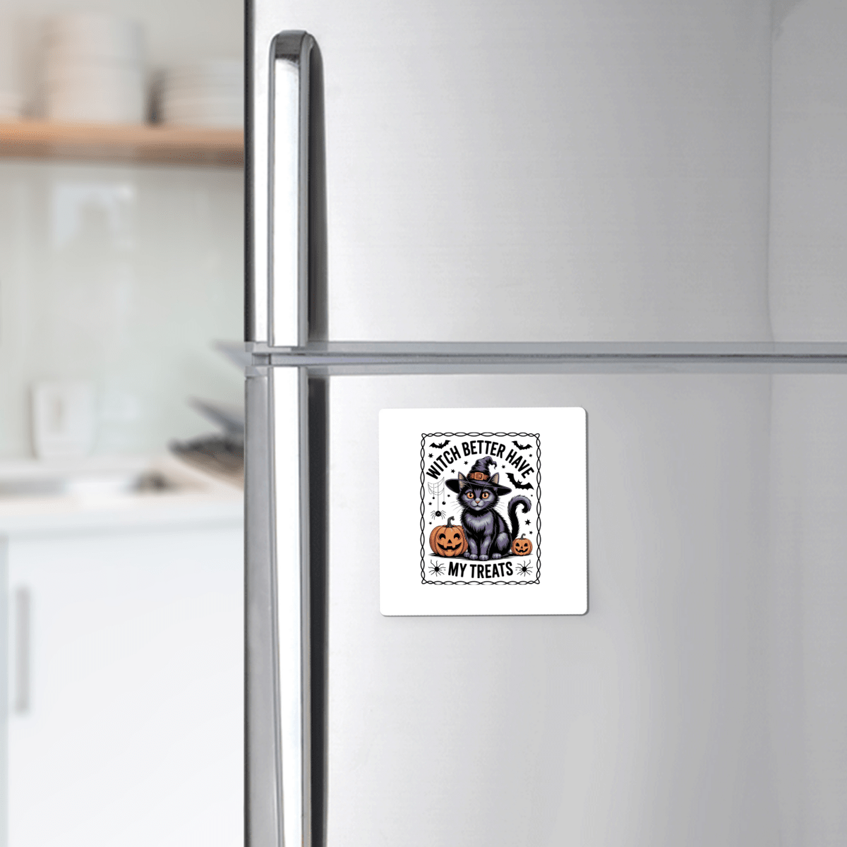 A refrigerator displays the Mirabilia Boutique Black Cat Witch Magnet, featuring a cat in a witch hat, pumpkin, and "Witch Better Have My Treats" text. Dishes are visible on the kitchen counter in the background.