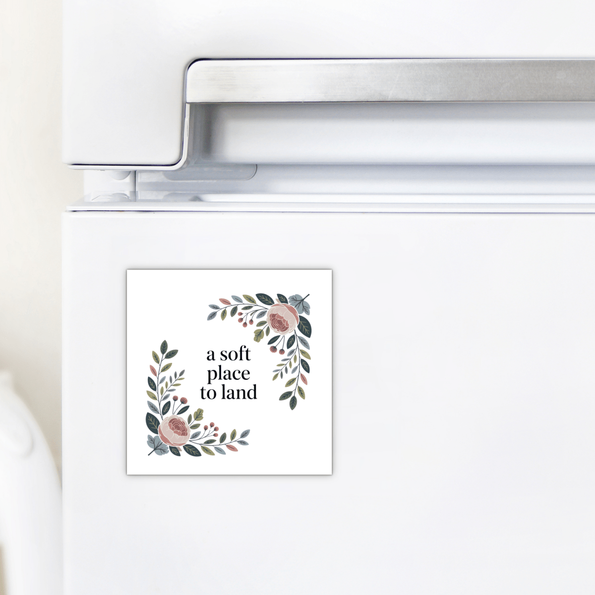 The A Soft Place to Land Floral Magnet by Mirabilia Boutique features pink and green botanical art and the text "a soft place to land," bringing cottagecore charm to your kitchen décor.
