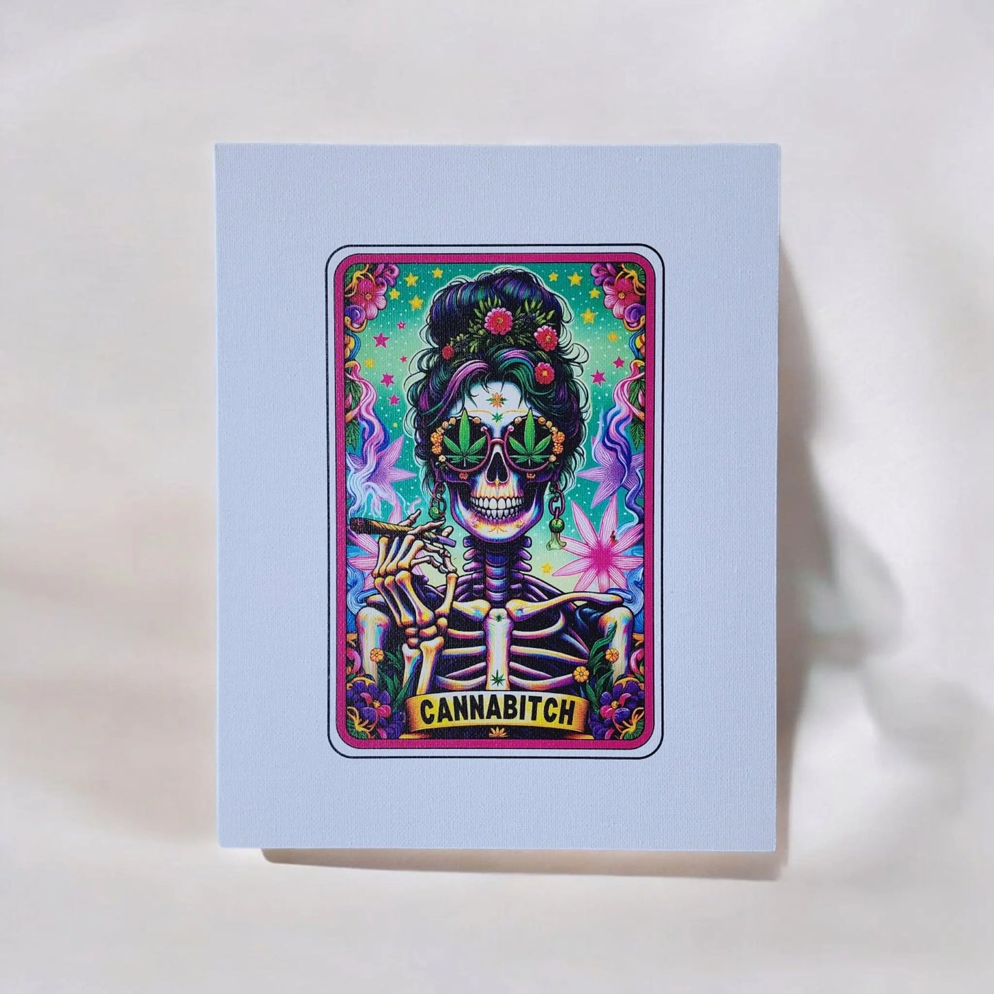 The Cannabitch 8x10 Canvas Sign from Mirabilia Boutique features a dynamic tarot card-style artwork showcasing a skeleton with vibrant, rolled hair. The skeleton wears large sunglasses shaped like cannabis leaves and holds a lit joint, set against an energetic backdrop of neon colors and cannabis leaves. The word "CANNABITCH" is prominently displayed in the design.