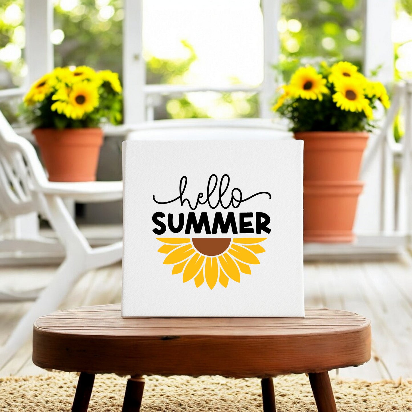 The Mirabilia Boutique Hello Summer Sunflower Canvas Sign – 8x8 Wall Art features a sunflower graphic on canvas, displayed on a wooden table among potted sunflowers and white chairs for bright, cheerful wall decor.