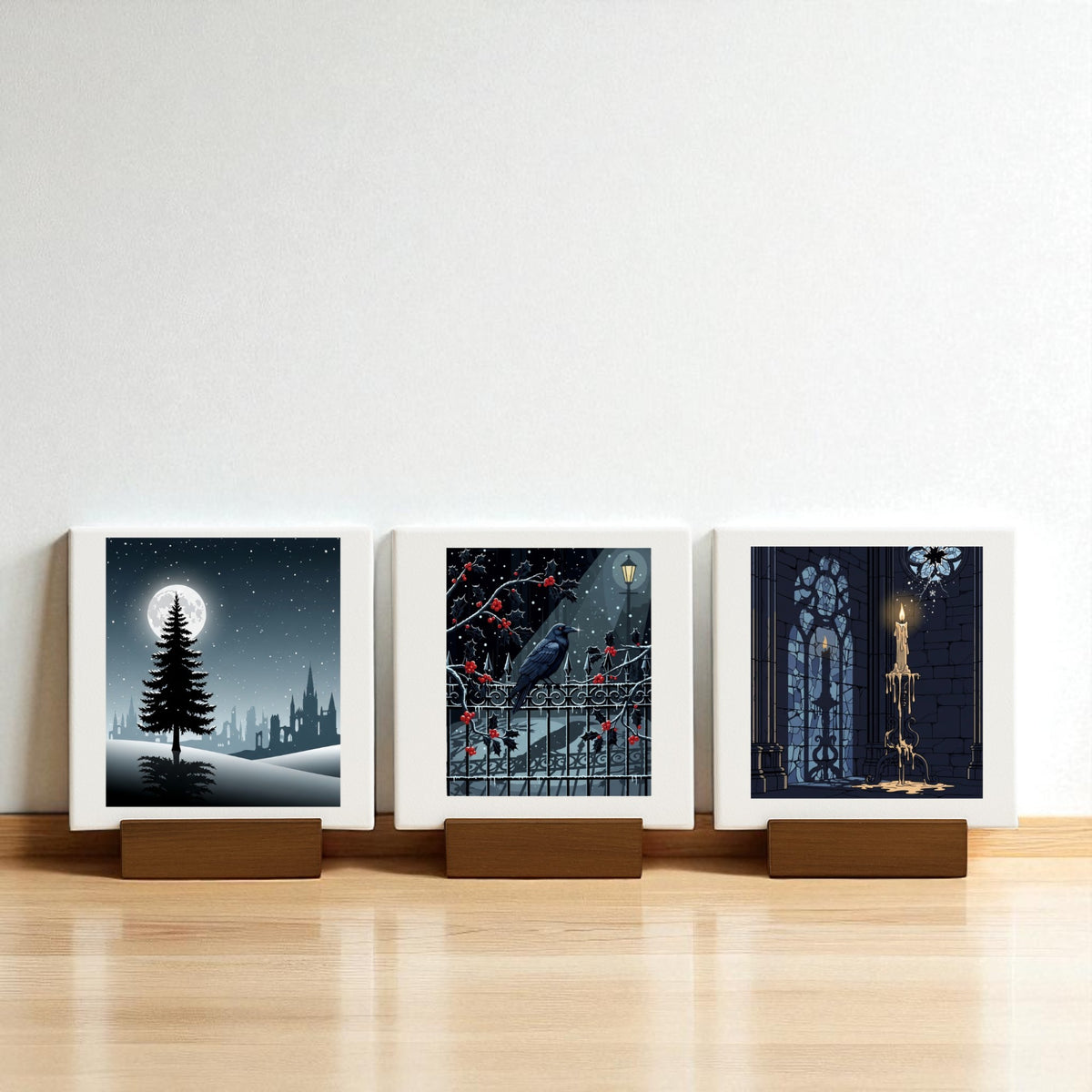 The Christmas Noir Midnight Trio by Mirabilia Boutique features three square prints on wooden stands—a moonlit tree, a raven with red berries, and a candle in a gothic window—ideal gothic holiday decor for your Christmas Noir Mini Canvas collection.