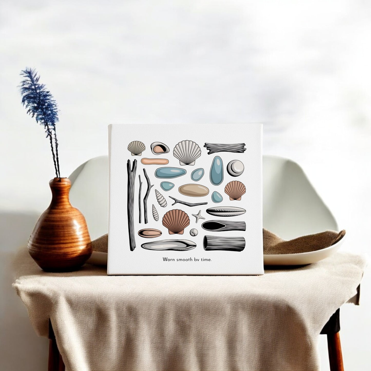 The Worn Smooth by Time Canvas – Coastal Shell & Driftwood Art from Mirabilia Boutique is a white, square coastal wall art piece with blue-gray imagery, perfect beside a vase for adding serene home decor vibes.