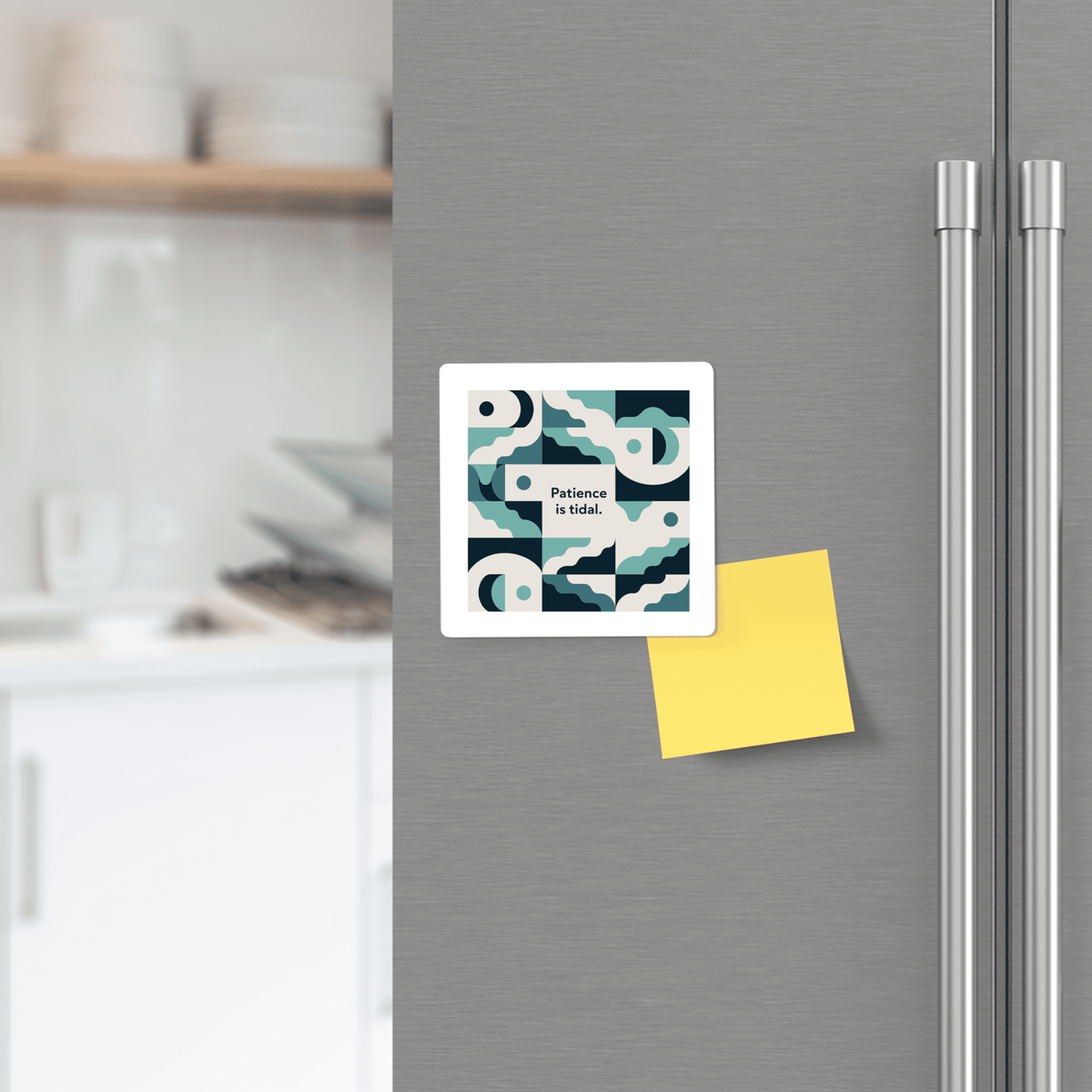 A Mirabilia Boutique "Patience Is Tidal Magnet – Ocean-Inspired Calm Quote" with blue and white patterns is displayed on a stainless steel fridge beside a yellow sticky note in a modern kitchen.