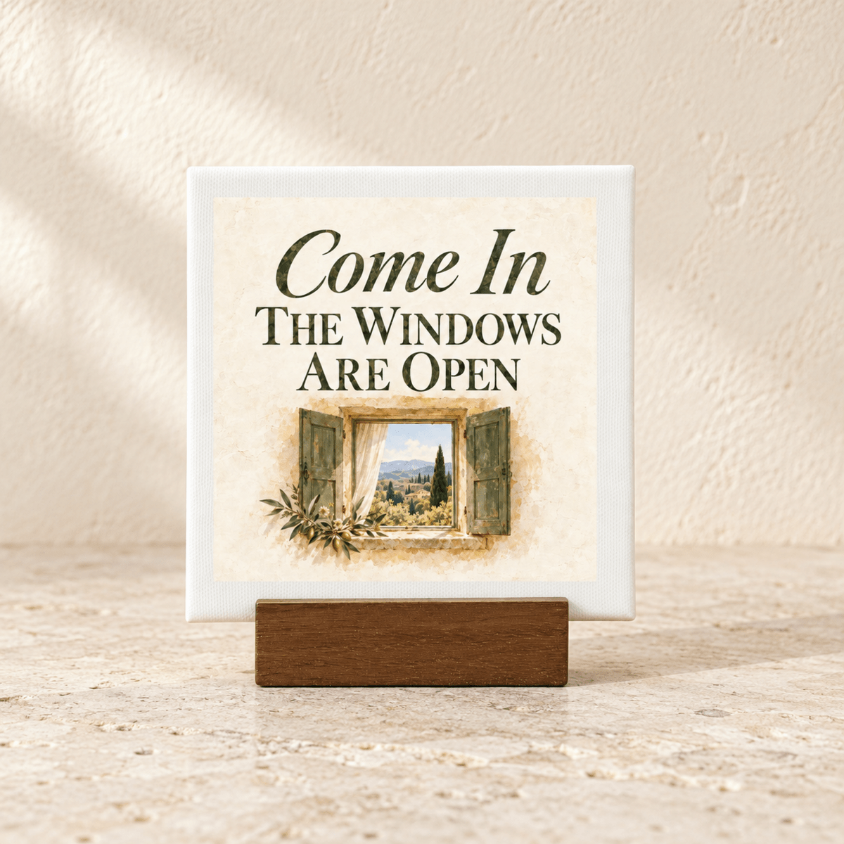 Come In Mini Canvas Sign in a wooden stand reading “Come In The Windows Are Open” above an illustration of an open window looking out onto a landscape.