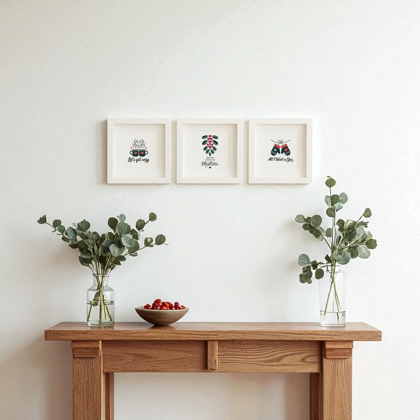 A wooden console table holds vases and cherries, while above, the Romantic Holiday Wall Art Trio | 5x5 Framed Gift Set from Mirabilia Boutique adds a minimalist, romantic touch—perfect as a couple’s gift or festive holiday wall decor.