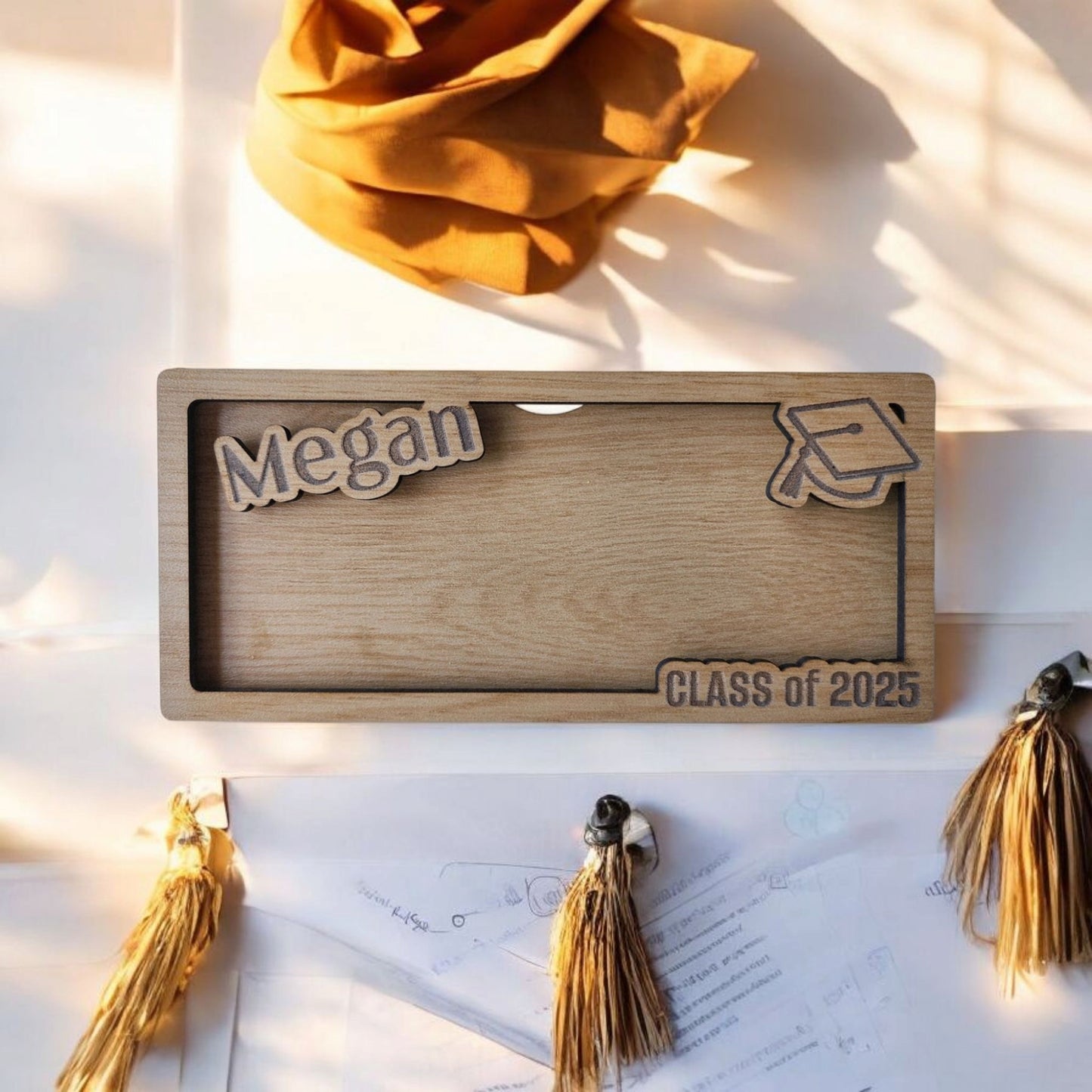 The Mirabilia Boutique Personalized Graduation Money Holder is a custom wood cash gift for the Class of 2025, engraved with “Megan,” a graduation cap, and gold tassels—an ideal keepsake for celebrating grads.