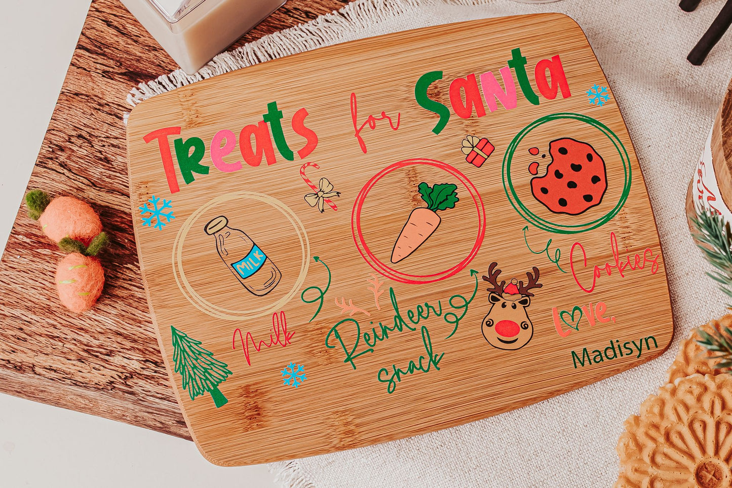 The Mirabilia Boutique Personalized Santa Treat Tray is a custom bamboo Christmas Eve board labeled for milk, cookies, and a carrot. This festive plate, ideal for Santa and his reindeer, features cute holiday designs and can include your child's name.