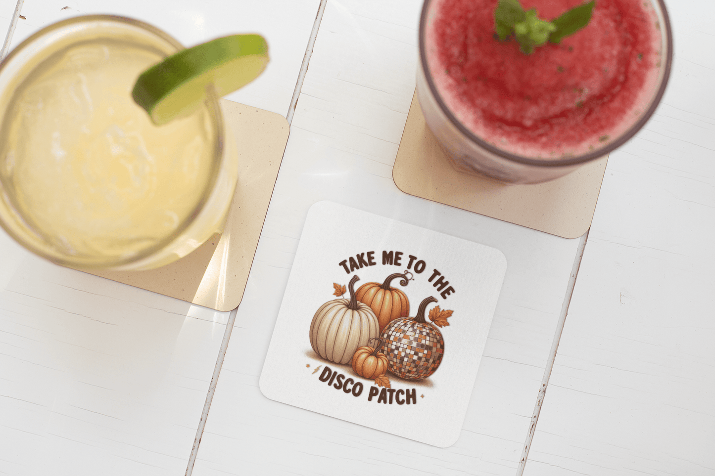 Two drinks rest on square coasters next to Mirabilia Boutique’s Disco Patch Pumpkin Coaster, featuring pumpkins and a disco ball—perfect retro fall decor for parties.