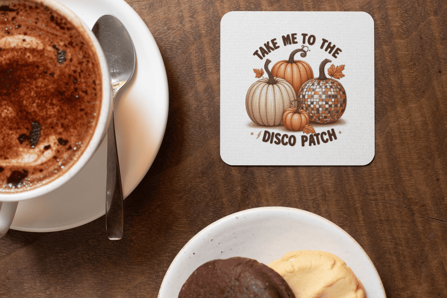 A cup of hot chocolate and cookies sit beside Mirabilia Boutique's Disco Patch Pumpkin Coaster Set—retro fall decor featuring festive pumpkins, including a disco ball design—perfect for cozy entertaining and autumn parties.