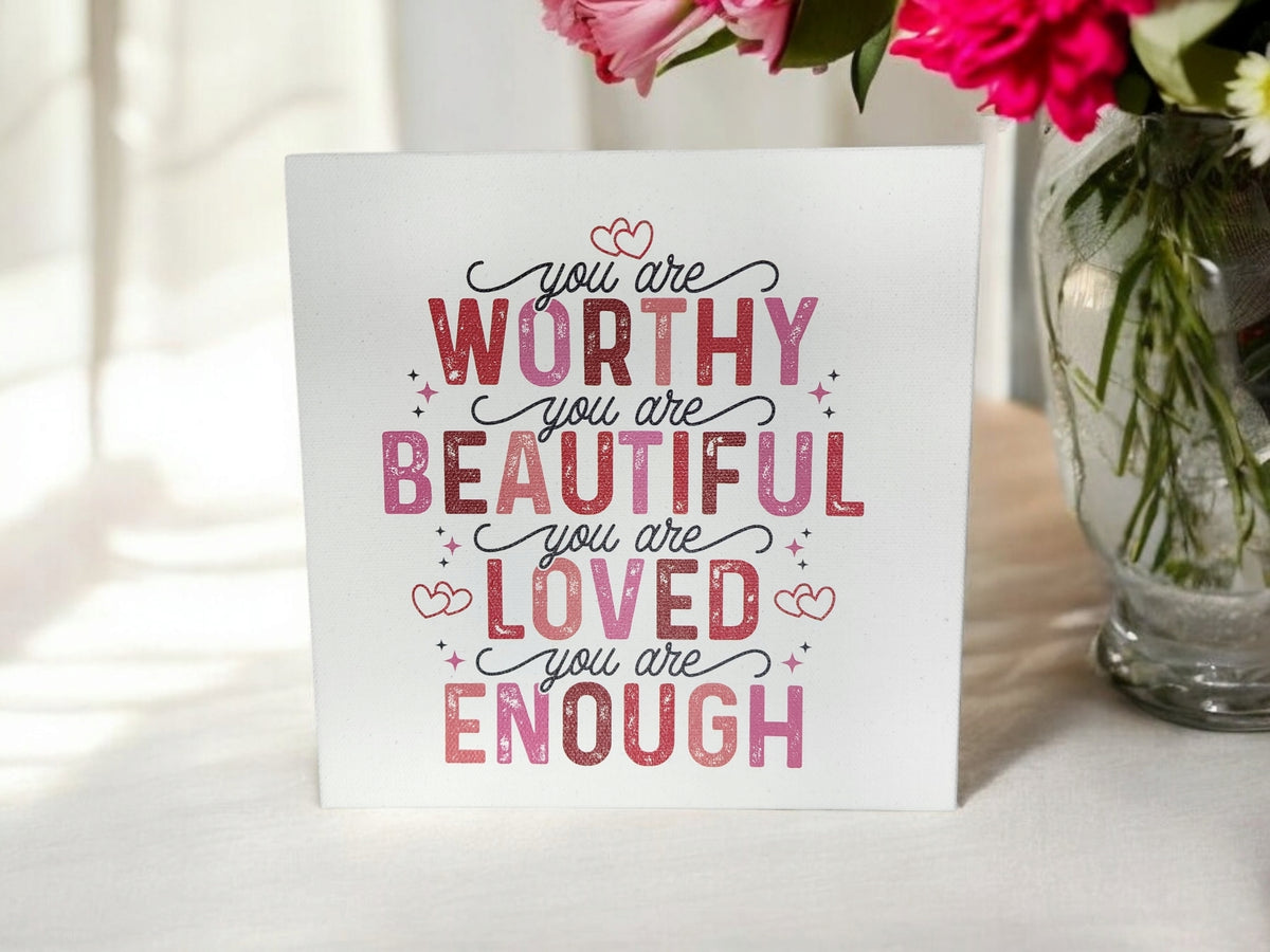 The You Are Worthy Affirmation Sign by Mirabilia Boutique is an 8x8 canvas wall art for women or teens featuring uplifting messages—“You are worthy, you are beautiful, you are loved, you are enough”—in pink and red fonts.