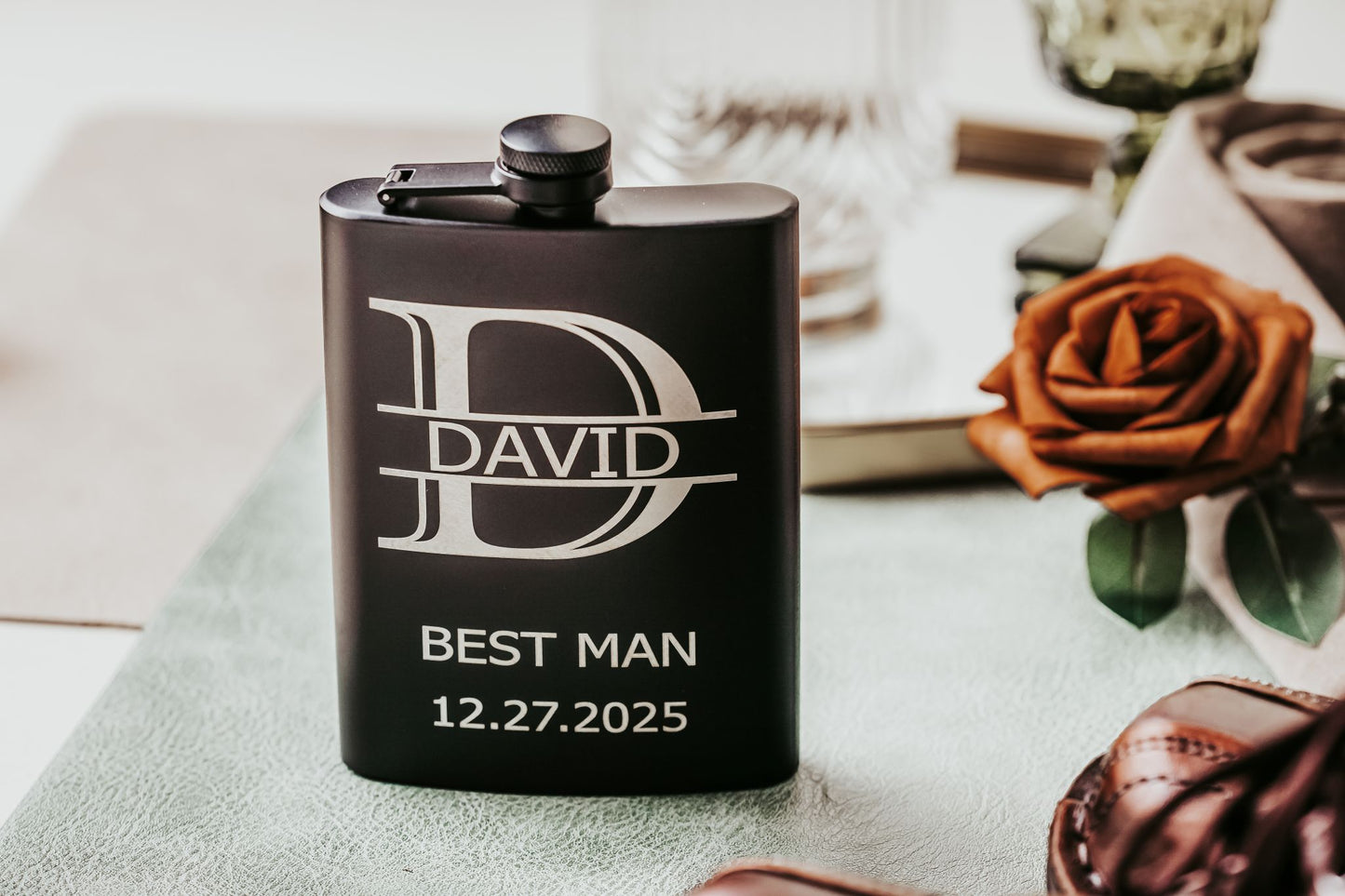 The Personalized Best Man Flask Gift Set by Mirabilia Boutique features a custom black flask engraved with "D," "DAVID," and "BEST MAN 12.27.2025." A stylish groomsmen present, it comes with accessories, ideal for your wedding party.