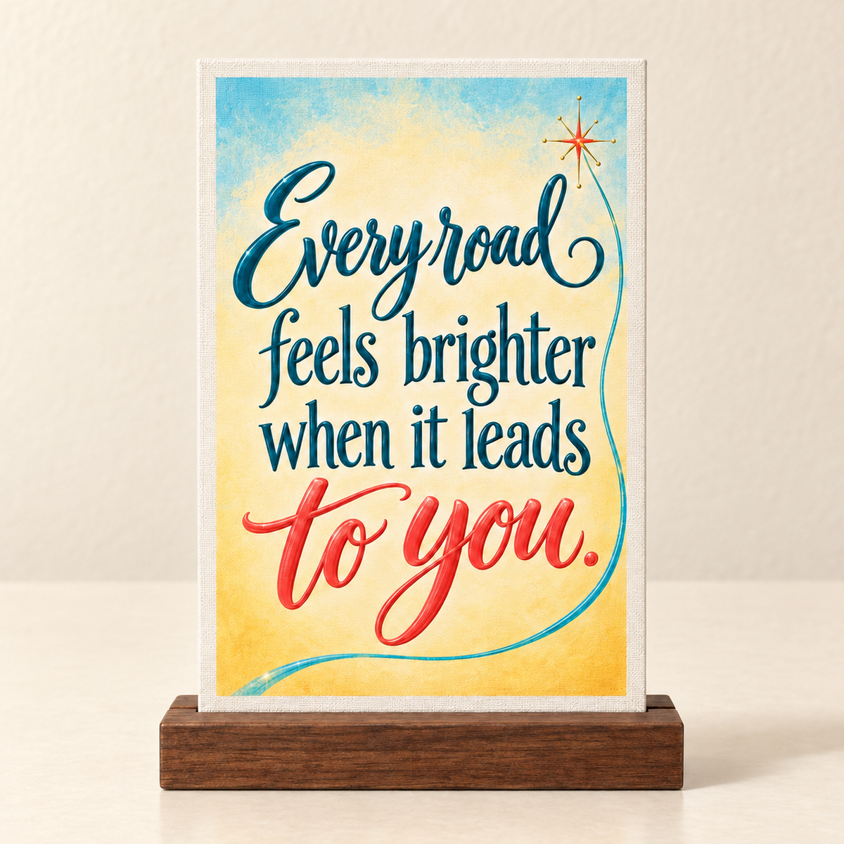 Every Road Feels Brighter Mini Sign | Chrome & Starlight rectangular mini canvas on a wooden stand, featuring expressive lettering, a starburst, and a swerving line on a yellow and blue background.