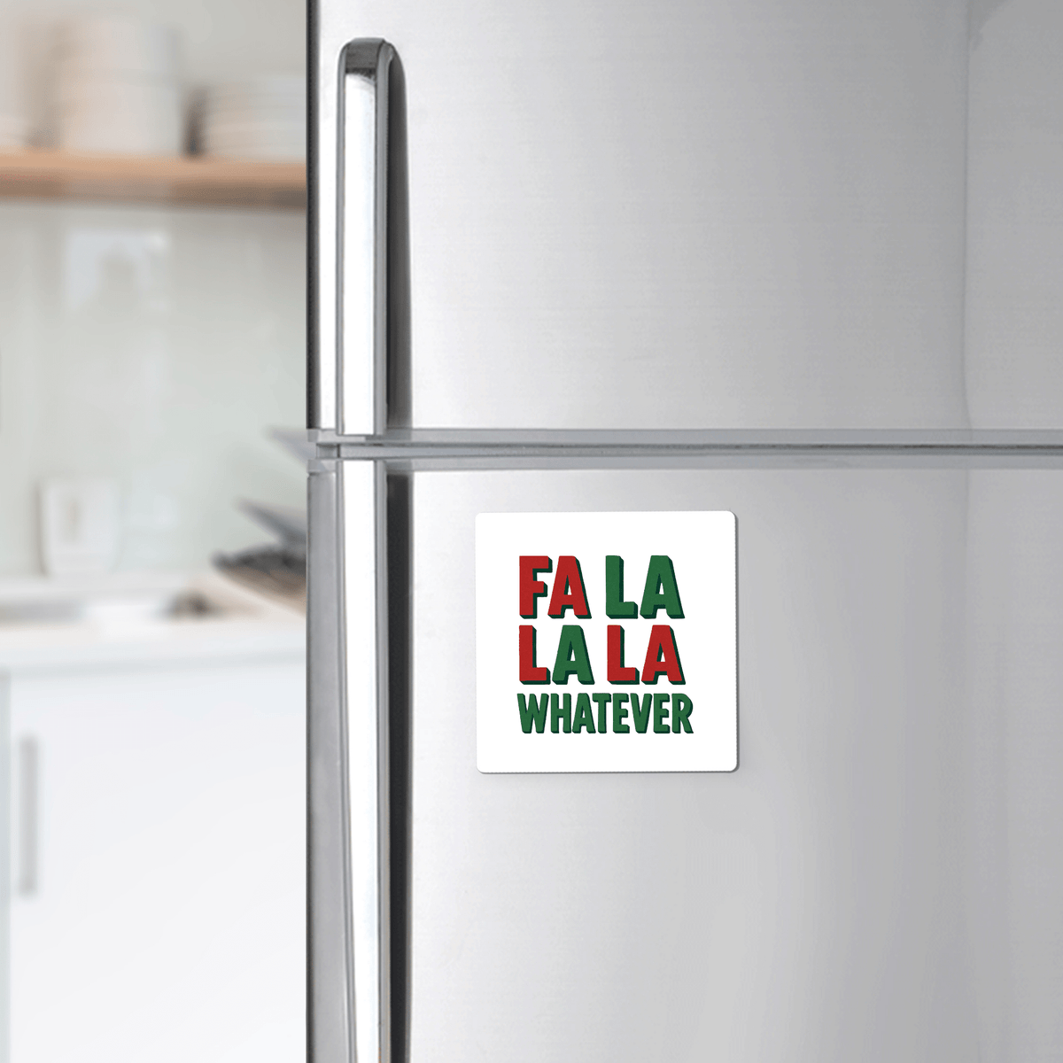 A silver refrigerator with the Mirabilia Boutique "Fa La La La Whatever" magnet—an amusing red, green, and white Christmas gift or stocking stuffer. Blurred kitchen in the background.