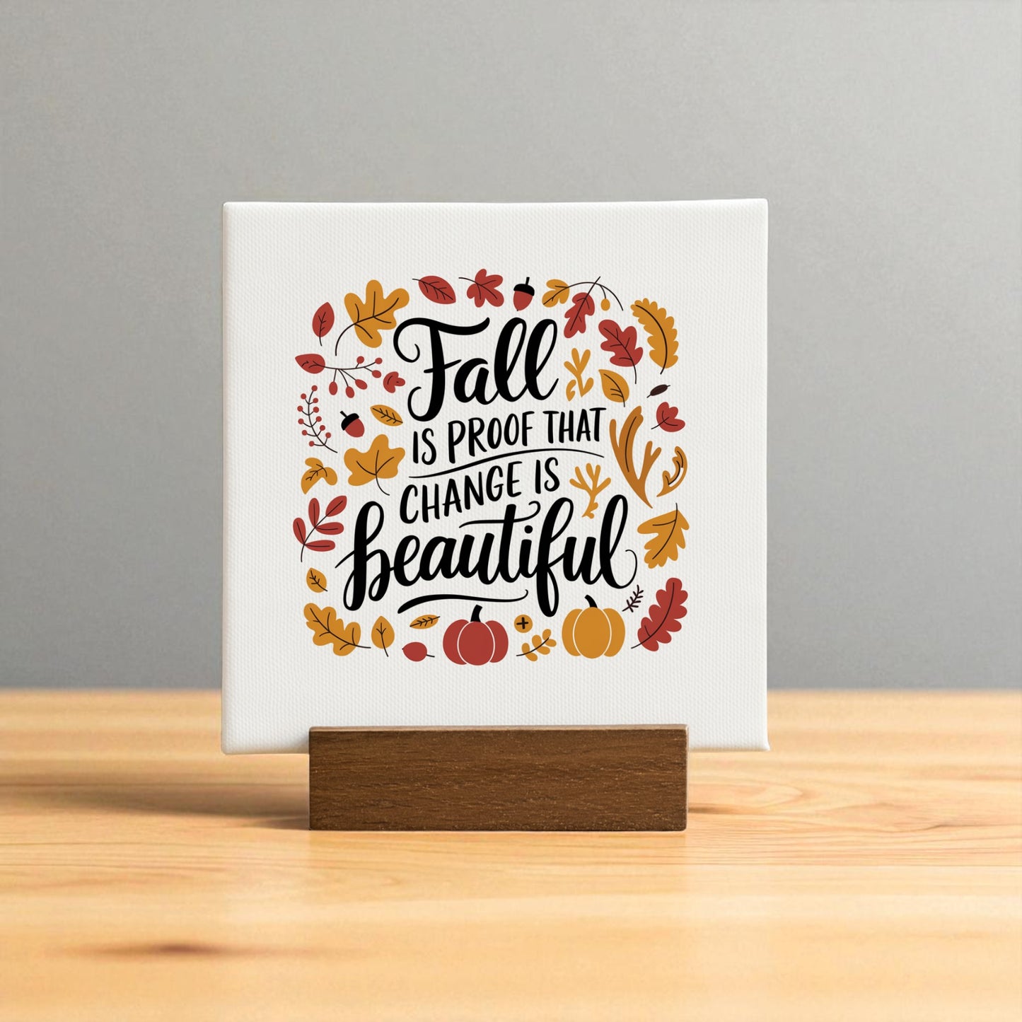 The Fall Is Proof Mini Sign by Mirabilia Boutique features “Fall is proof that change is beautiful” on a wooden stand, surrounded by leaves, an acorn, branches, and pumpkins—an inspirational autumn decor accent for your home.