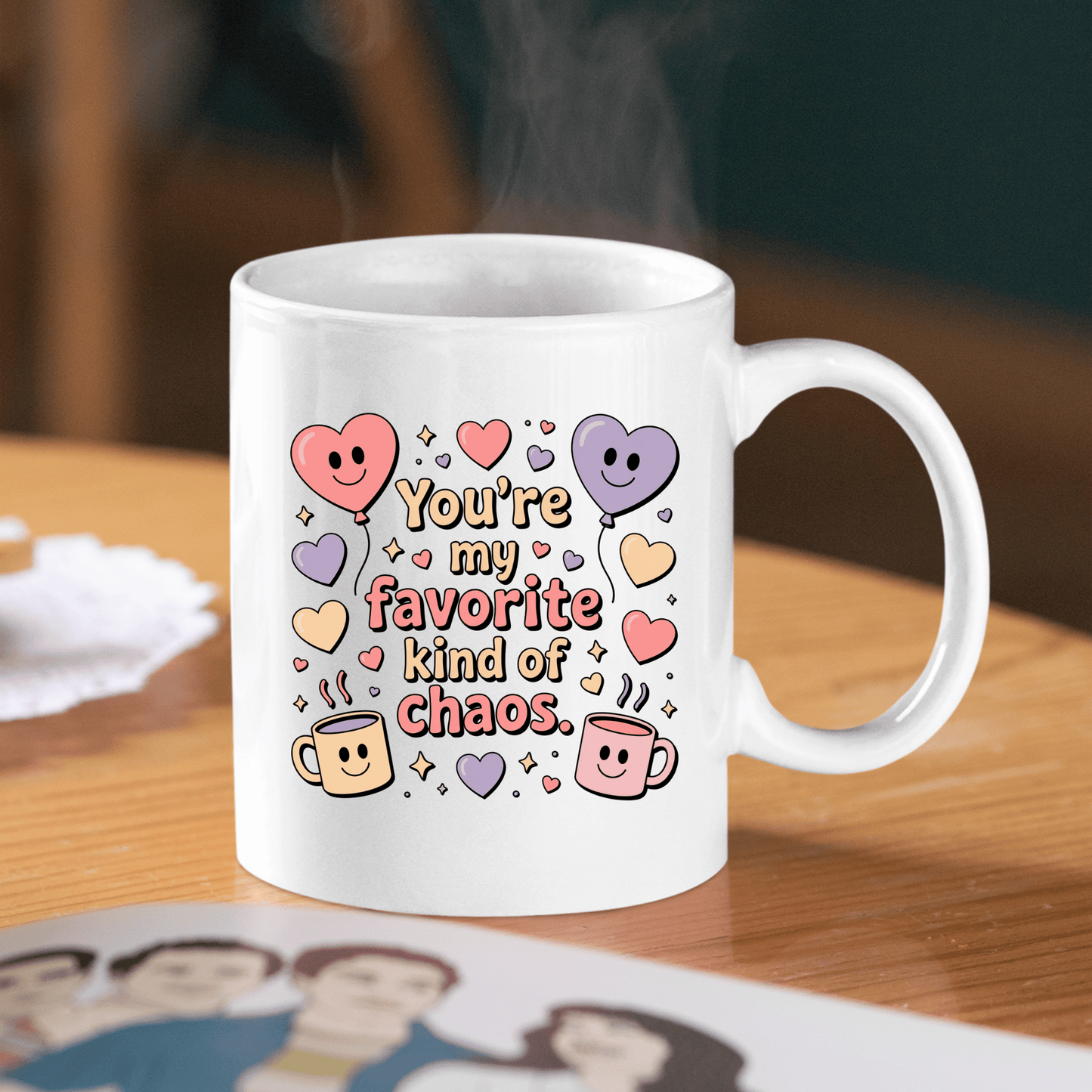 The Mirabilia Boutique Funny Best Friend Mug, “Favorite Kind of Chaos,” sits on a wooden table with colorful cartoon hearts and mugs, steam rising, and a blurred photo in the foreground—a perfect Valentine gift.