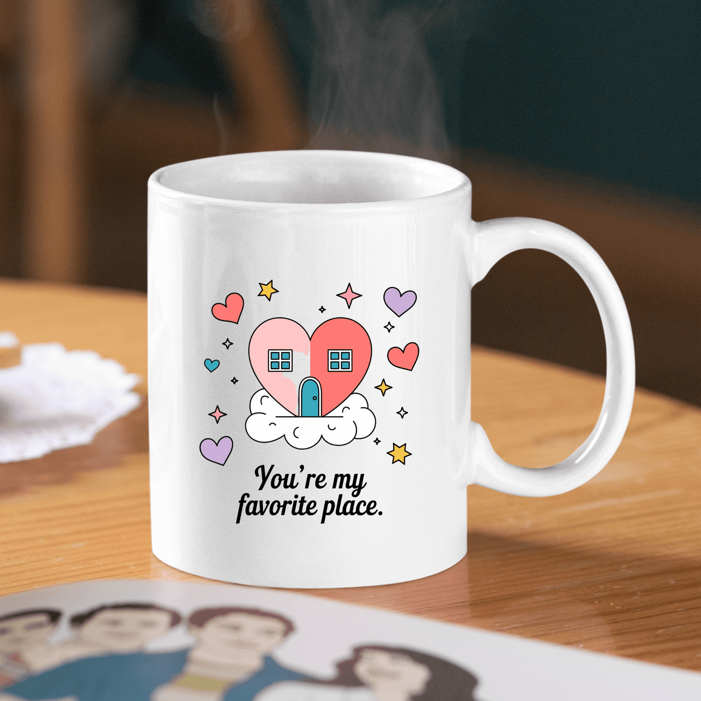 The Heart House Mug by Mirabilia Boutique features a heart-shaped house, colorful hearts, and clouds with the phrase "You're my favorite place," making it the perfect gift mug for someone special.