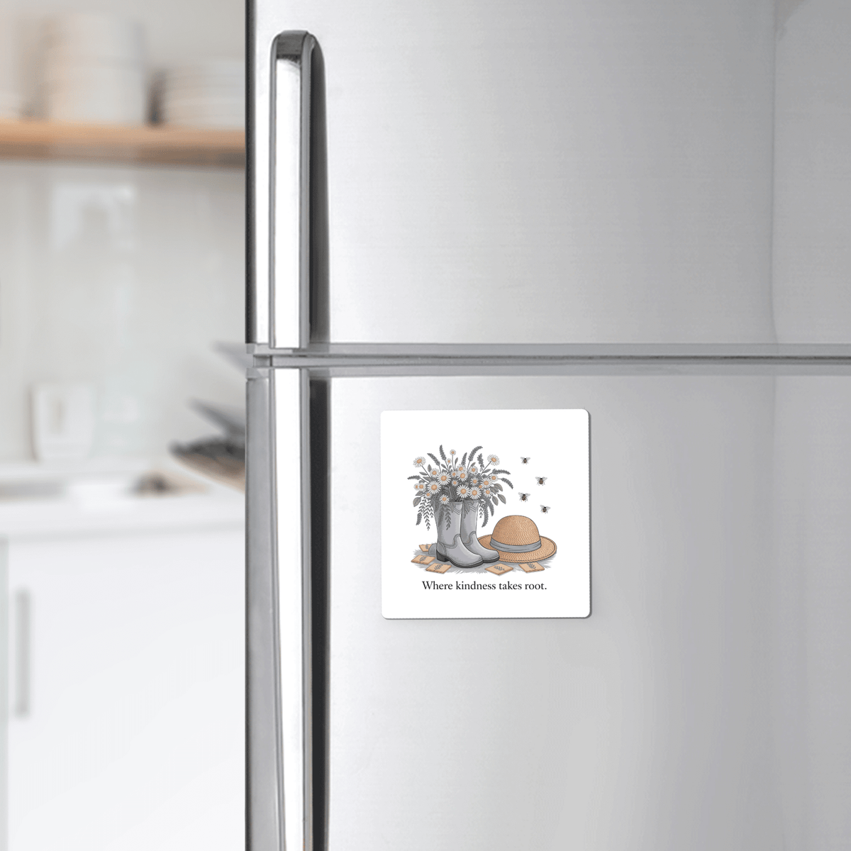 The Mirabilia Boutique Kindness Garden Magnet features floral boots, wildflowers, a straw hat, and bees with the quote "Where kindness takes root." The magnet adds charm to any refrigerator or kitchen decor.