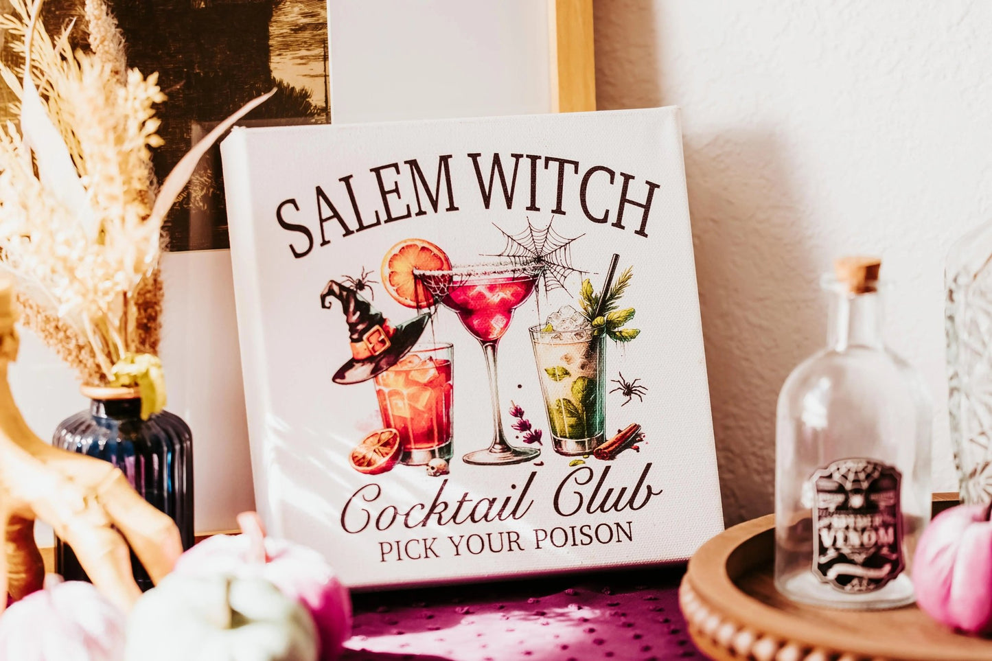 The Mirabilia Boutique Salem Witch Cocktail Club Halloween Canvas (8x8) adds spooky bar decor with "Pick Your Poison" and witchy Halloween touches—cocktails, witch hat, bottles, spider web, and autumn accents.