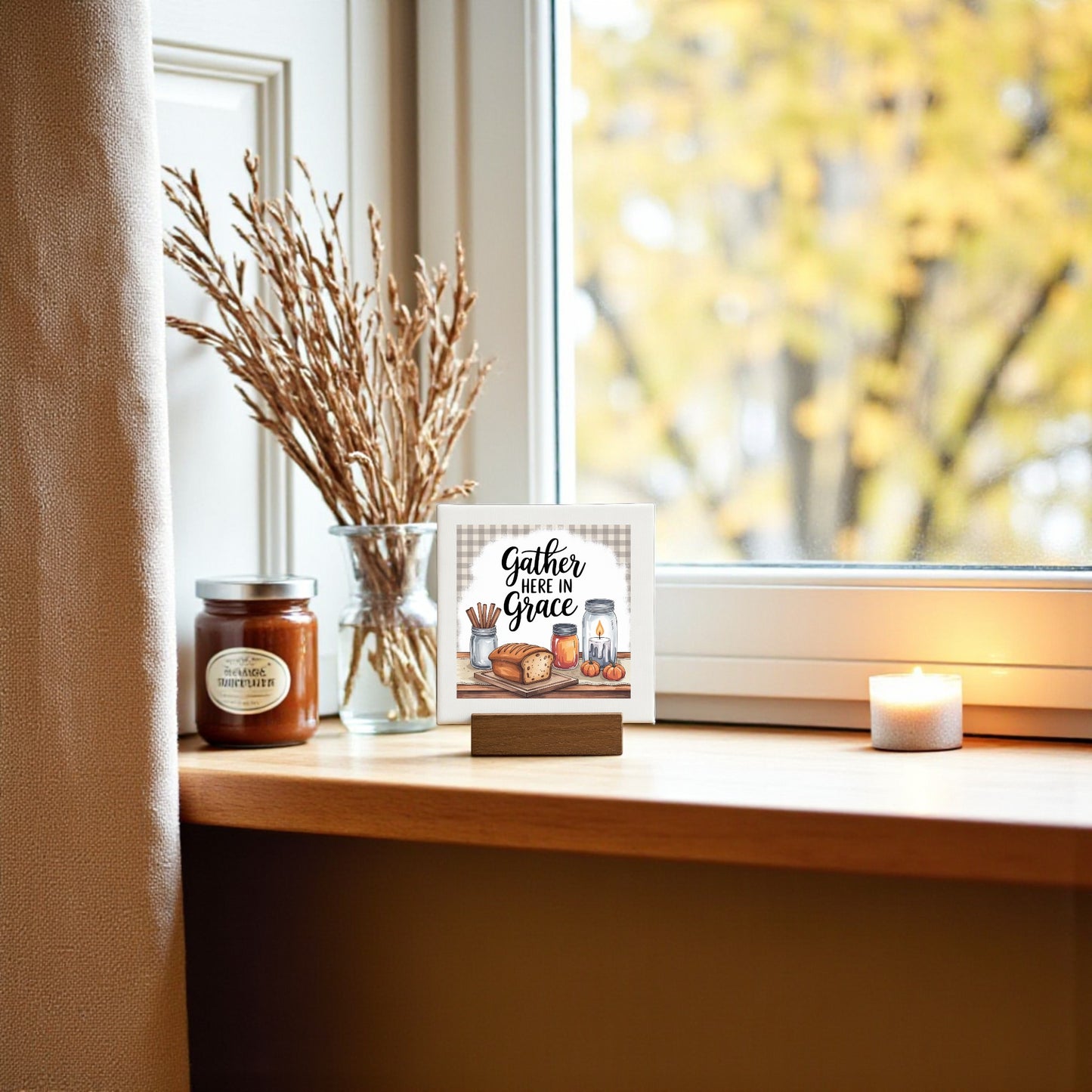 Create cozy farmhouse decor with Mirabilia Boutique’s Mini Gather Here in Grace 4x4 sign beside a "Cinnamon" candle and dried wheat by the window—ideal as a thoughtful Thanksgiving gift.