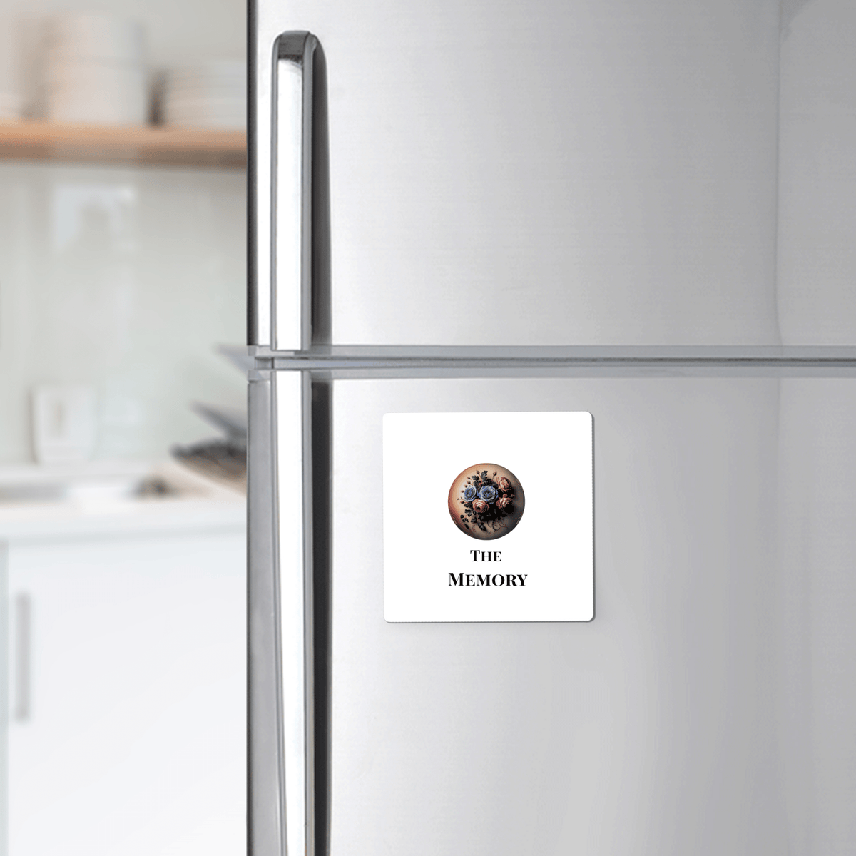 A silver fridge features Mirabilia Boutique’s “The Memory” Dead Regency Magnet—a white gothic floral decor piece with a bouquet and “THE MEMORY” text, adding unique minimal gothic style to your kitchen.
