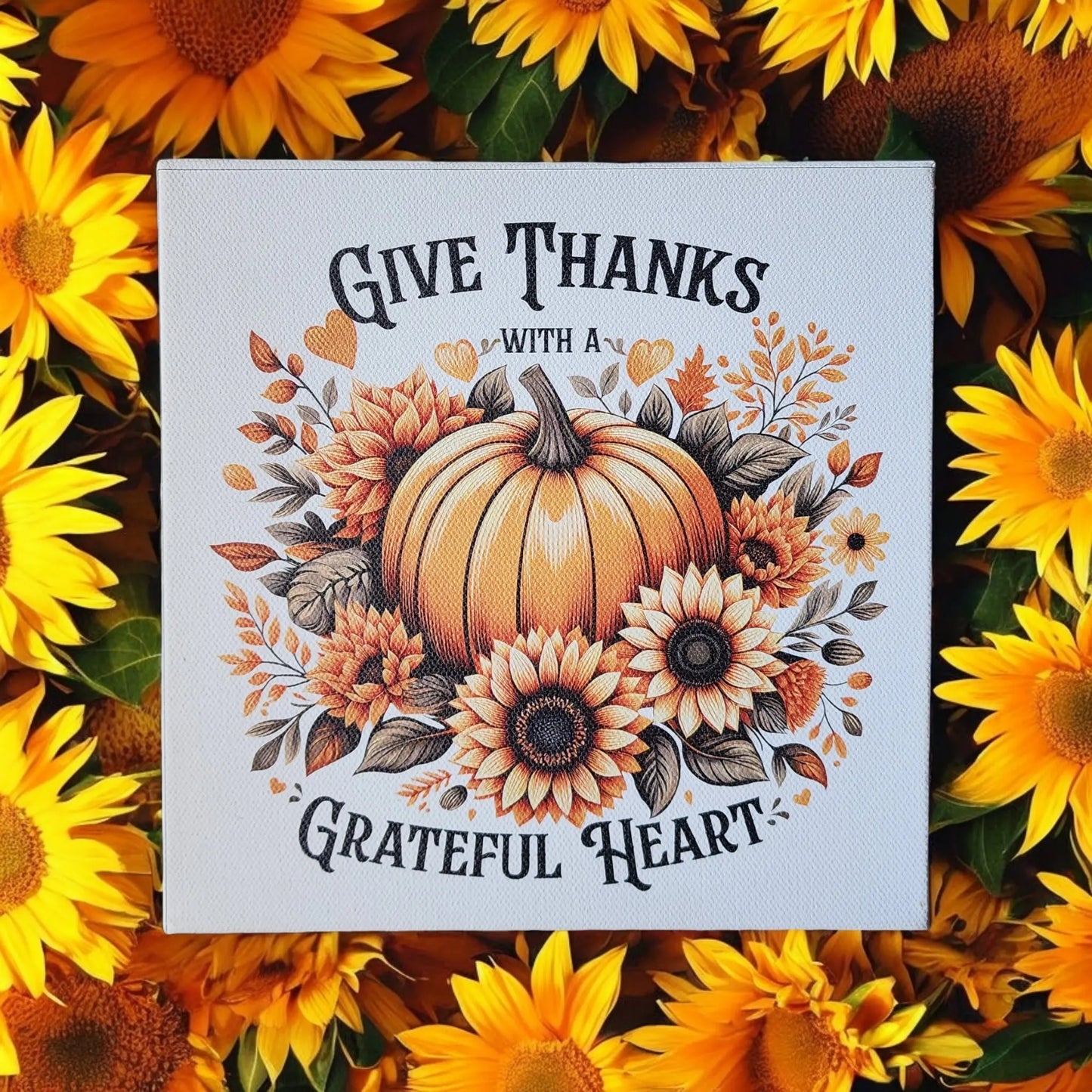 A seasonal home decor sign from Mirabilia Boutique, titled "Give Thanks With a Grateful Heart," features a charming design with a pumpkin and sunflowers. Perfect for autumn, this Thanksgiving decoration beautifully embodies gratitude and warmth.