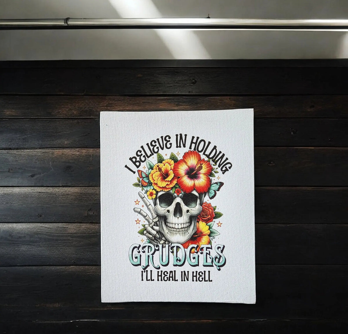 Mirabilia Boutique’s “I Believe in Holding Grudges” Canvas Print (8x10) features a skull with flowers and bold text, perfect Gothic wall art for those who love dark humor and want striking decor for their space.