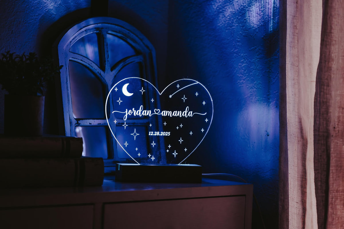 The Mirabilia Boutique Personalized Couples LED Night Light—a custom heart acrylic sign with engraved names and wedding date—glows on the nightstand, making a magical bedroom décor piece or a unique wedding gift.