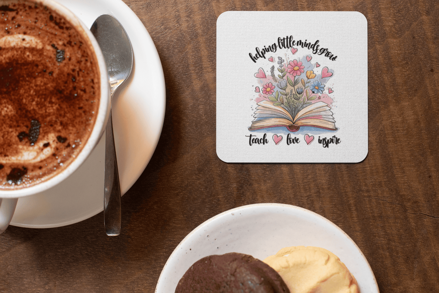 Enjoy a cup of hot chocolate and cookies with Mirabilia Boutique's Helping Little Minds Grow Coasters—a set of 4 featuring flowers blooming from an open book and the words "helping little minds grow, teach, love, inspire." Perfect for teacher gifts!.