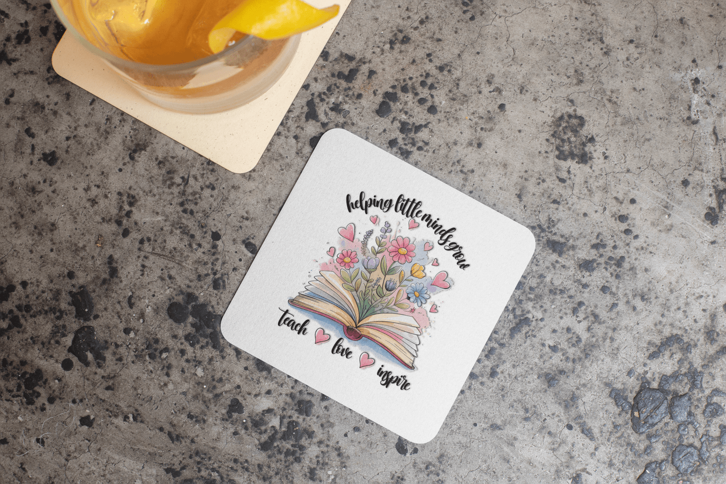 The Helping Little Minds Grow Coasters by Mirabilia Boutique feature an open book with flowers and hearts plus the words "helping little minds grow, teach, love, inspire." This set of 4 makes a perfect teacher gift.