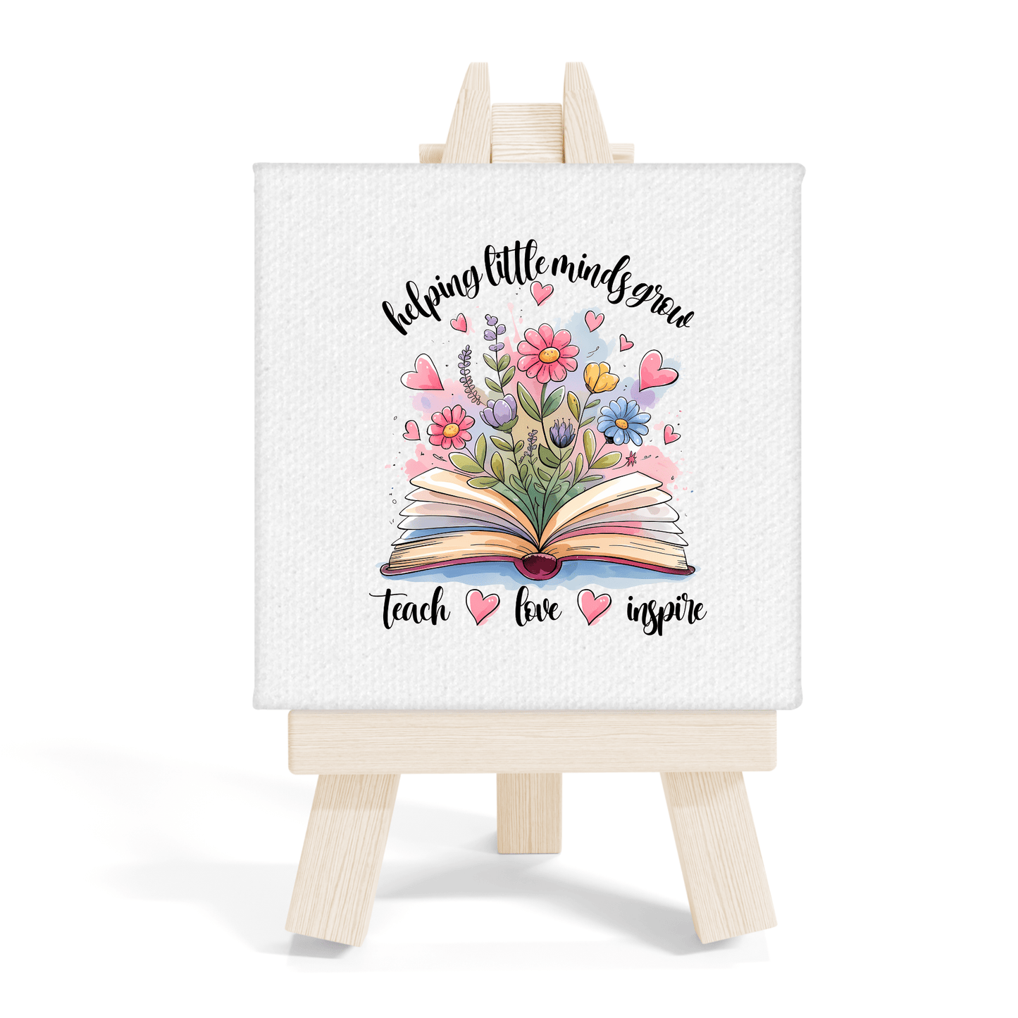 The Helping Little Minds Grow Mini Canvas with easel by Mirabilia Boutique features an open book with flowers and hearts, plus the phrase: "helping little minds grow, teach, love, inspire." Ideal for classroom decor or as a teacher gift.