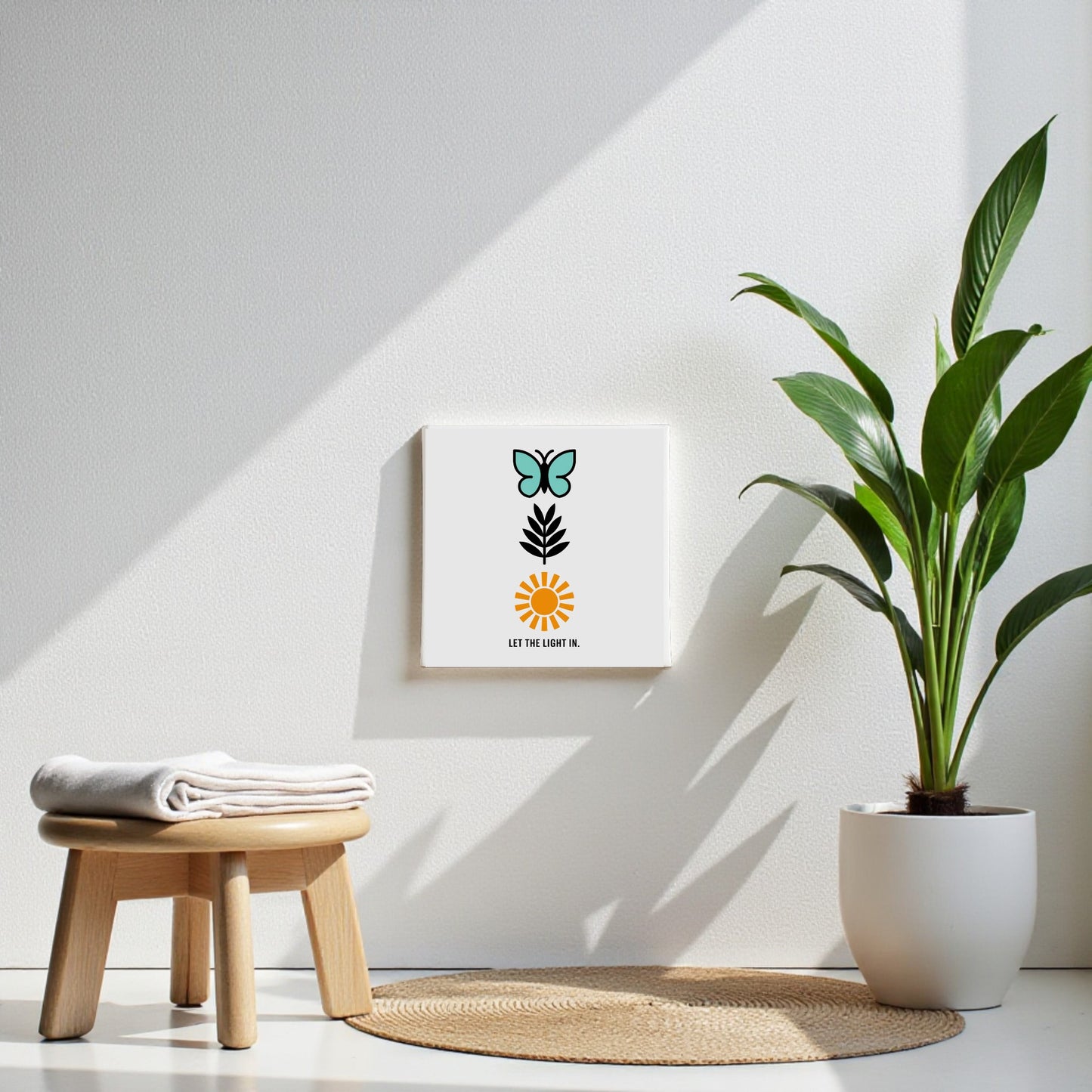 A minimalist, sunlit room features a potted plant, wooden stool with folded towels, and Mirabilia Boutique’s Let the Light In Canvas – Butterfly Sun Wall Art for an inspiring touch.