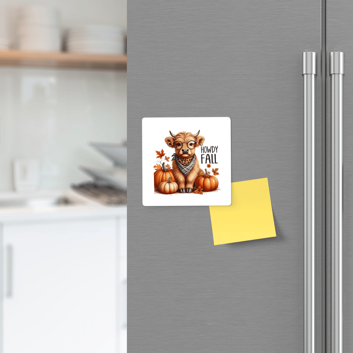 The Howdy Fall Highland Cow Magnet by Mirabilia Boutique adds cute autumn charm to a stainless steel fridge in a modern farmhouse kitchen, pictured alongside a blank yellow sticky note.