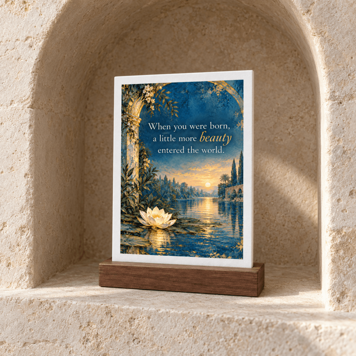A Little More Beauty Friendship Mini Sign featuring a painting of a sunset over a lake with a lotus in the foreground and the text “When you were born, a little more beauty entered the world” on a wood base.