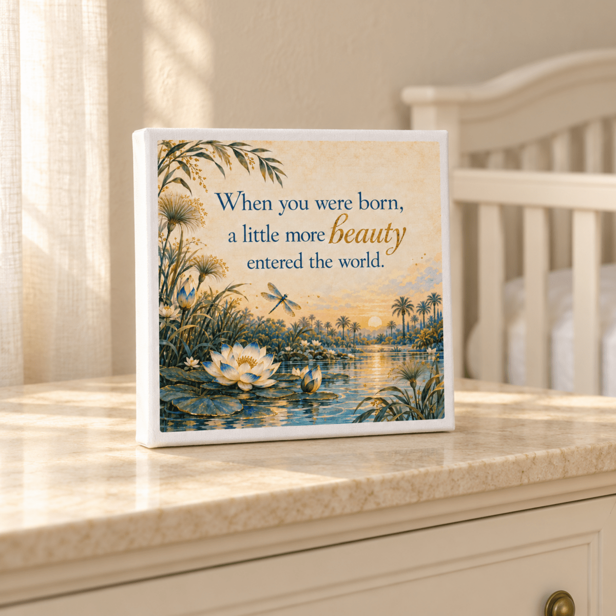 A square A Little More Beauty Canvas from Mirabilia Boutique showing a pond with lotus flowers and a dragonfly at sunset, featuring the text: “When you were born, a little more beauty entered the world.”