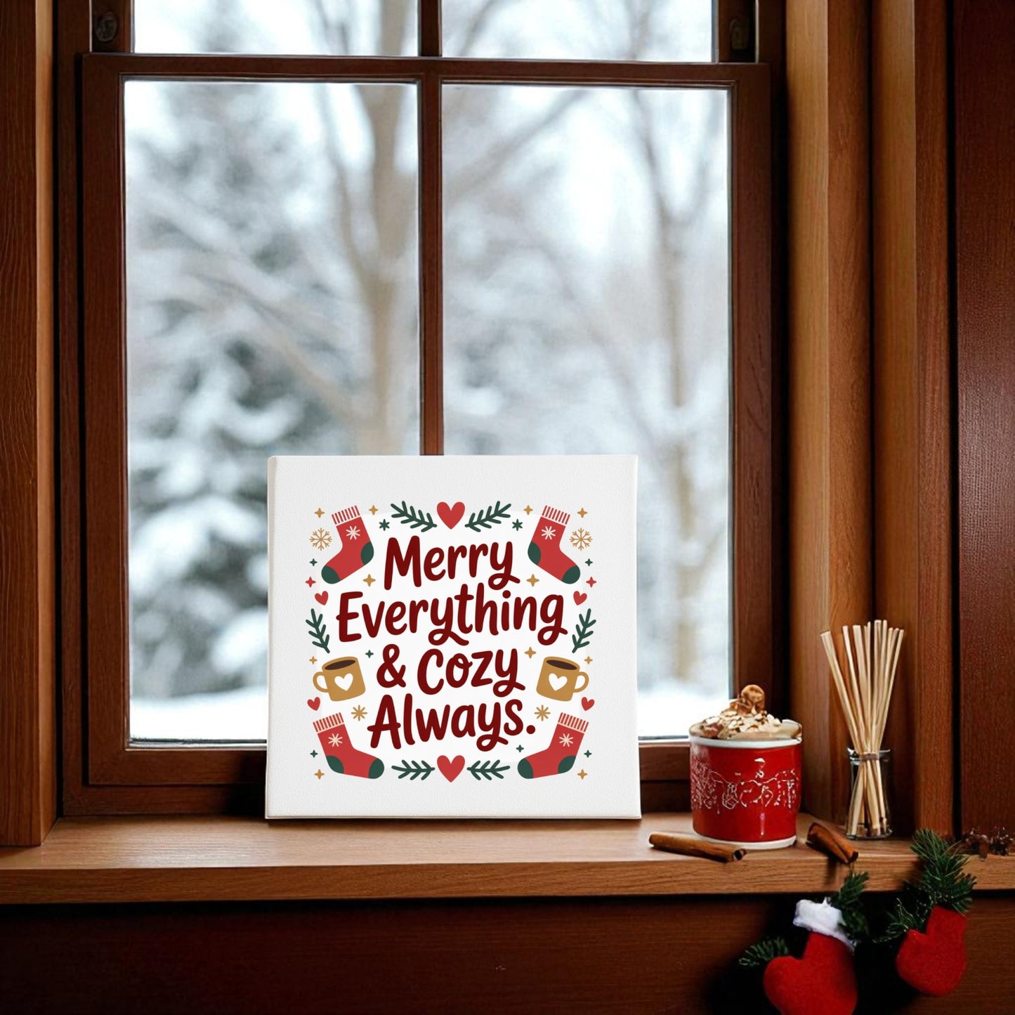 The Mirabilia Boutique 8x8 "Merry Everything & Cozy Always" canvas wall art sits on a wooden windowsill amid holiday decor, with a snowy winter view outside.