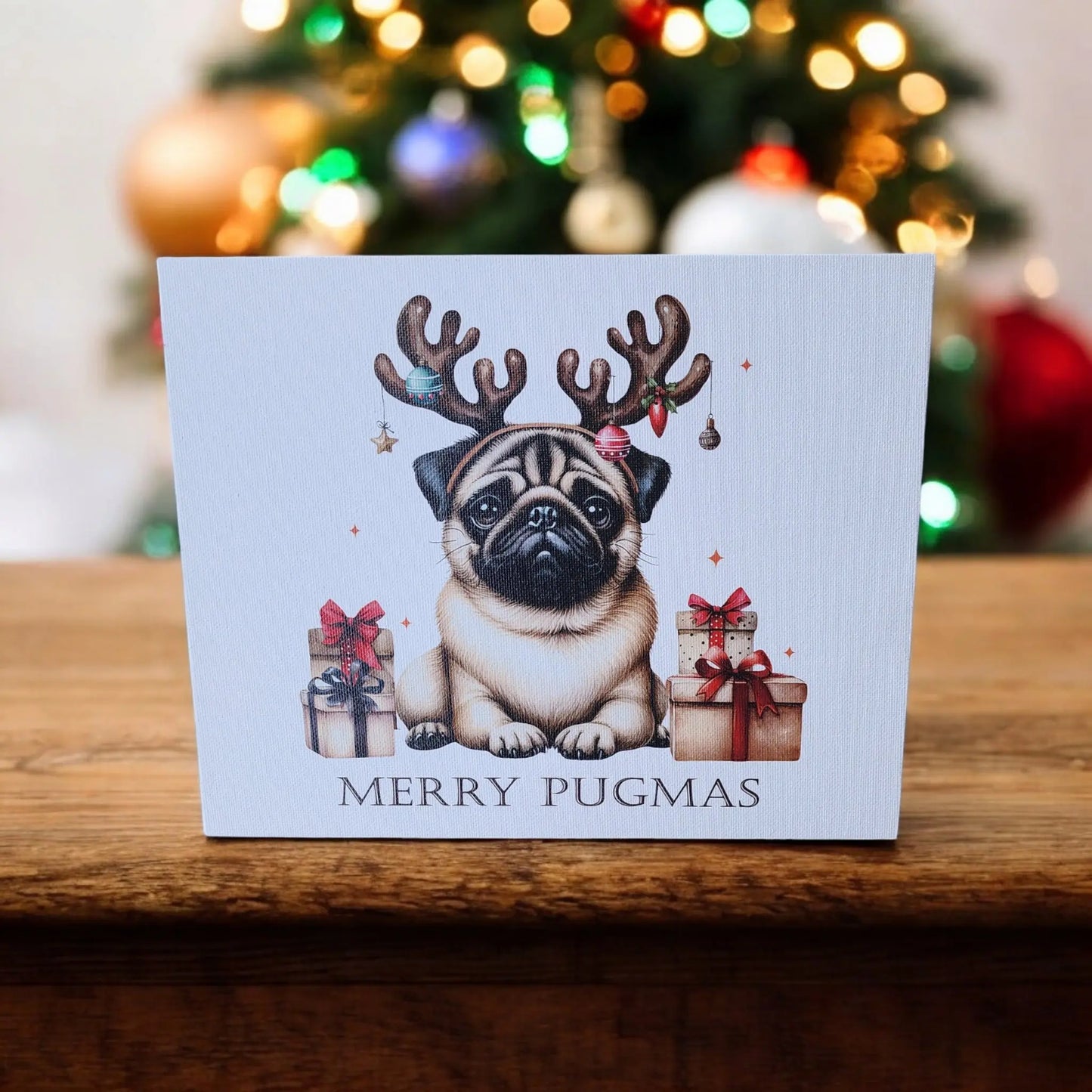 Introducing the "Merry Pugmas" 10x8 Canvas Sign by Mirabilia Boutique: A charming piece featuring an illustration of a pug wearing reindeer antlers, sitting amongst wrapped gifts. The sign joyfully declares "Merry Pugmas" at the bottom, against a backdrop of a blurred, decorated Christmas tree adorned with colorful holiday decor and lights.