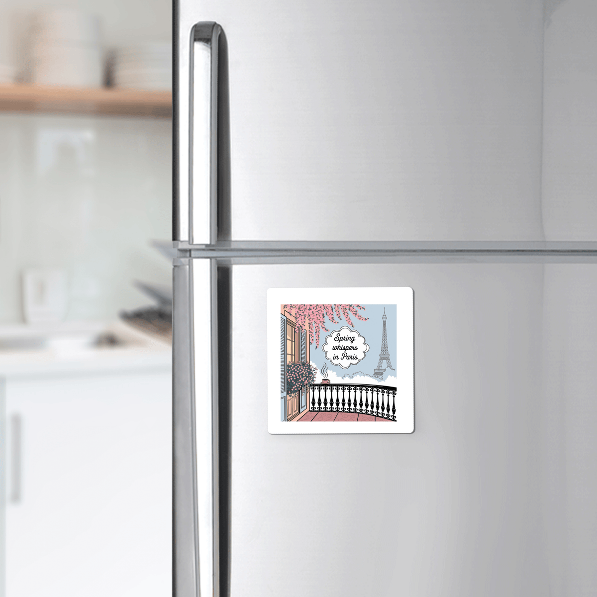 The Spring Whispers in Paris Magnet – Eiffel Tower View by Mirabilia Boutique features an illustrated Parisian balcony and the Eiffel Tower, with "Living in Paris" over a serene spring morning scene, perfect for your stainless steel refrigerator.