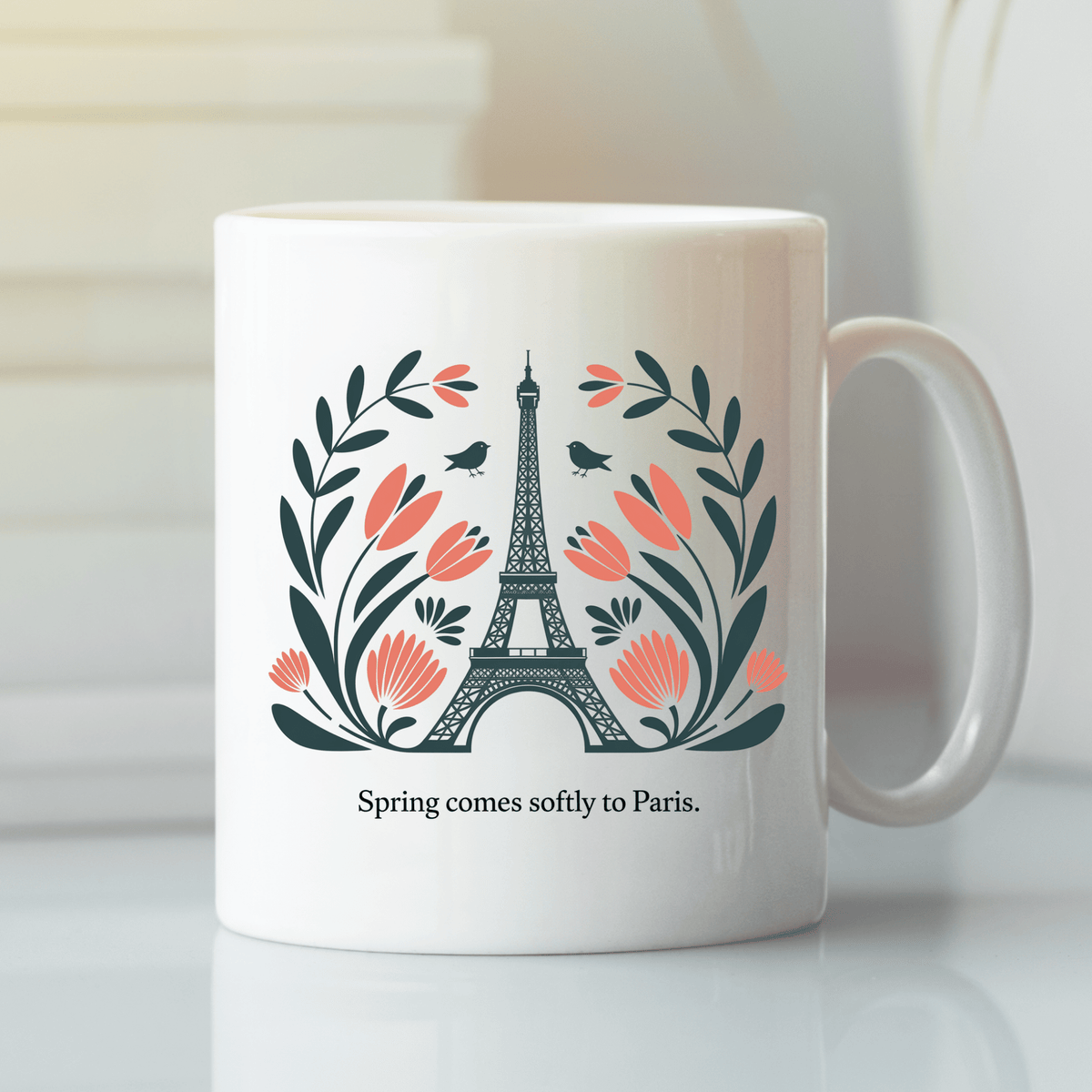 The Paris Spring Mug – Eiffel Tower & Floral Design by Mirabilia Boutique features the iconic tower with pink flowers, leaves, two small birds, and the phrase "Spring comes softly to Paris.