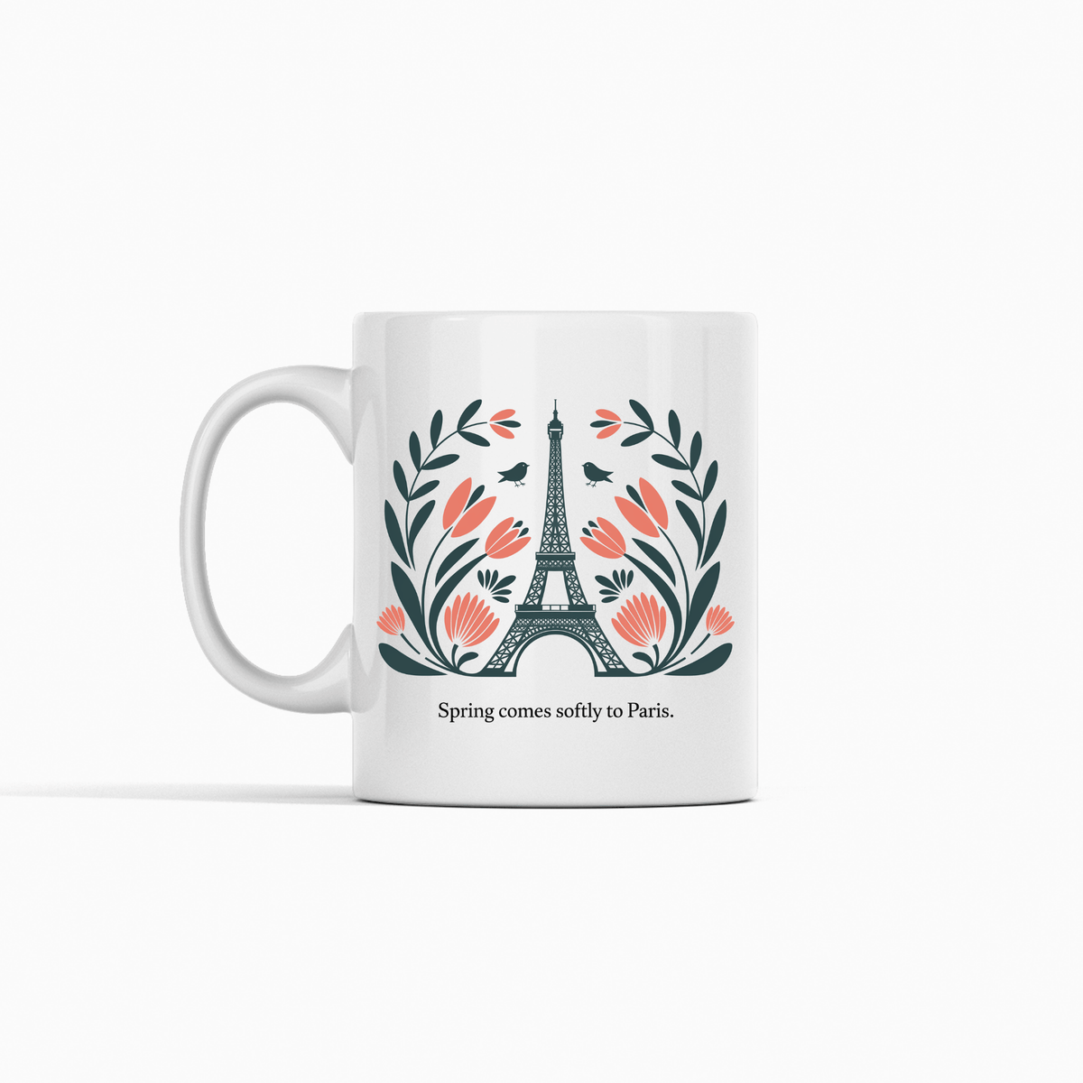 The Paris Spring Mug – Eiffel Tower & Floral Design by Mirabilia Boutique features the Eiffel Tower with pink flowers and green leaves, plus the phrase "Spring comes softly to Paris." A charming ceramic mug for dreamers and travelers.