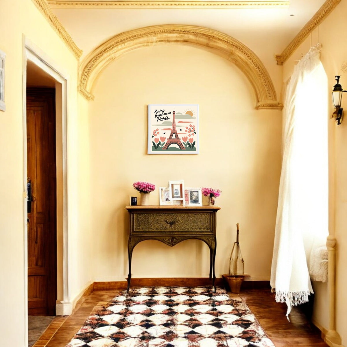 A hallway with cream walls, an arched ceiling, a vintage table with flowers and framed photos, patterned rug, and natural light is brought to life by Mirabilia Boutique’s "Spring Found Me in Paris – Eiffel Tower Art Canvas.