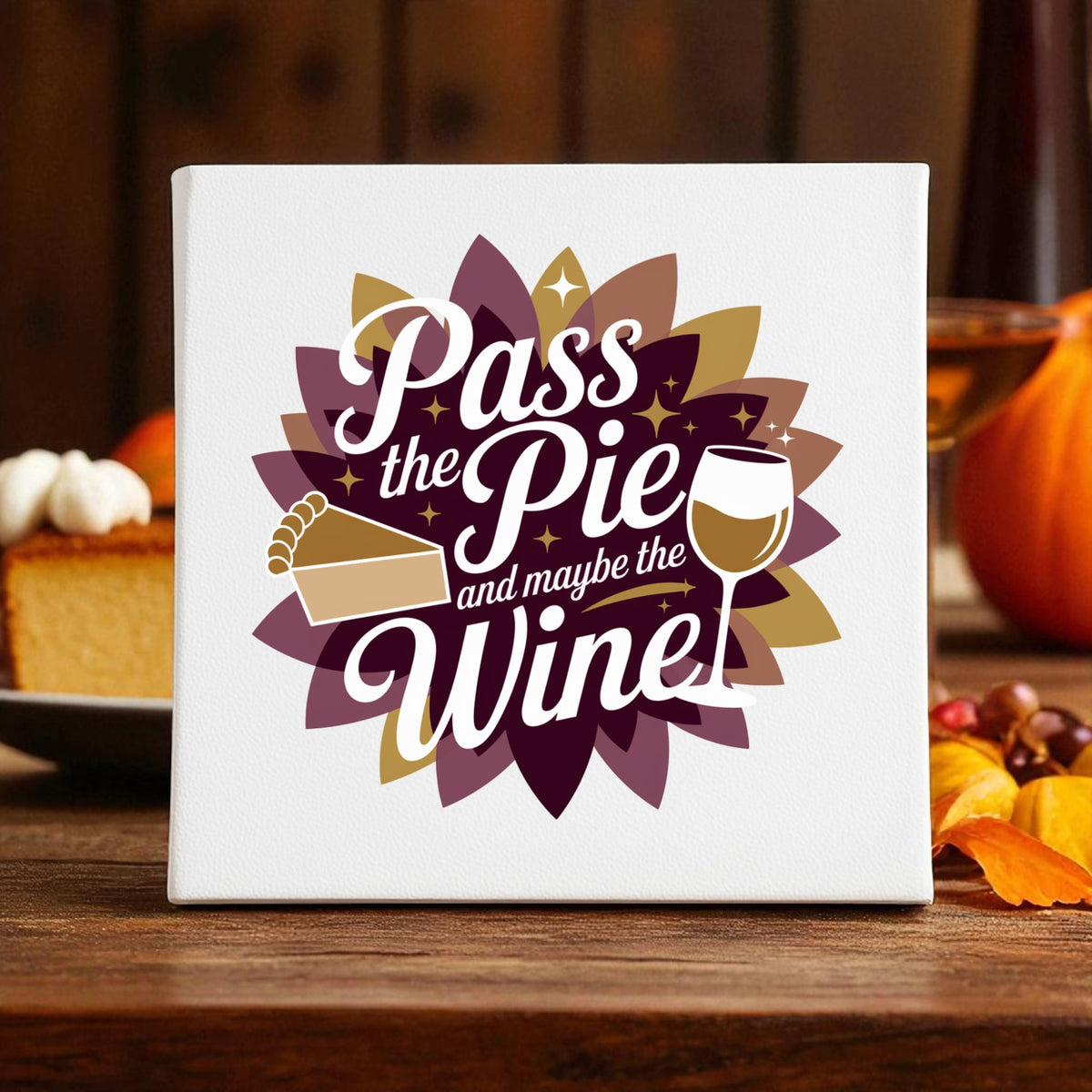 The "Pass the Pie and Maybe the Wine" canvas sign by Mirabilia Boutique features autumn leaves, a pumpkin, and pie—making it fun Thanksgiving decor for cozy fall gatherings.