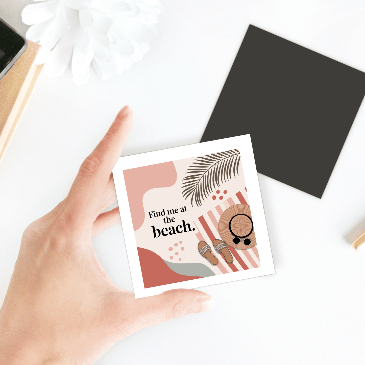 A hand holds the Mirabilia Boutique “Find Me at the Beach” Magnet, featuring abstract coastal art and sunglasses—ideal as a summer gift or playful decor for beach lovers.