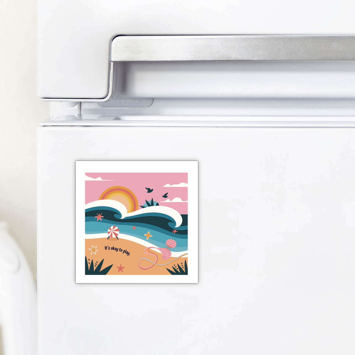 The Mirabilia Boutique It’s Okay to Play Magnet – Whimsical Ocean Joy features a vibrant beach scene with waves, sunrise, birds, starfish, seashells, and toys. The playful text on the fridge magnet reads: "It's okay to play.